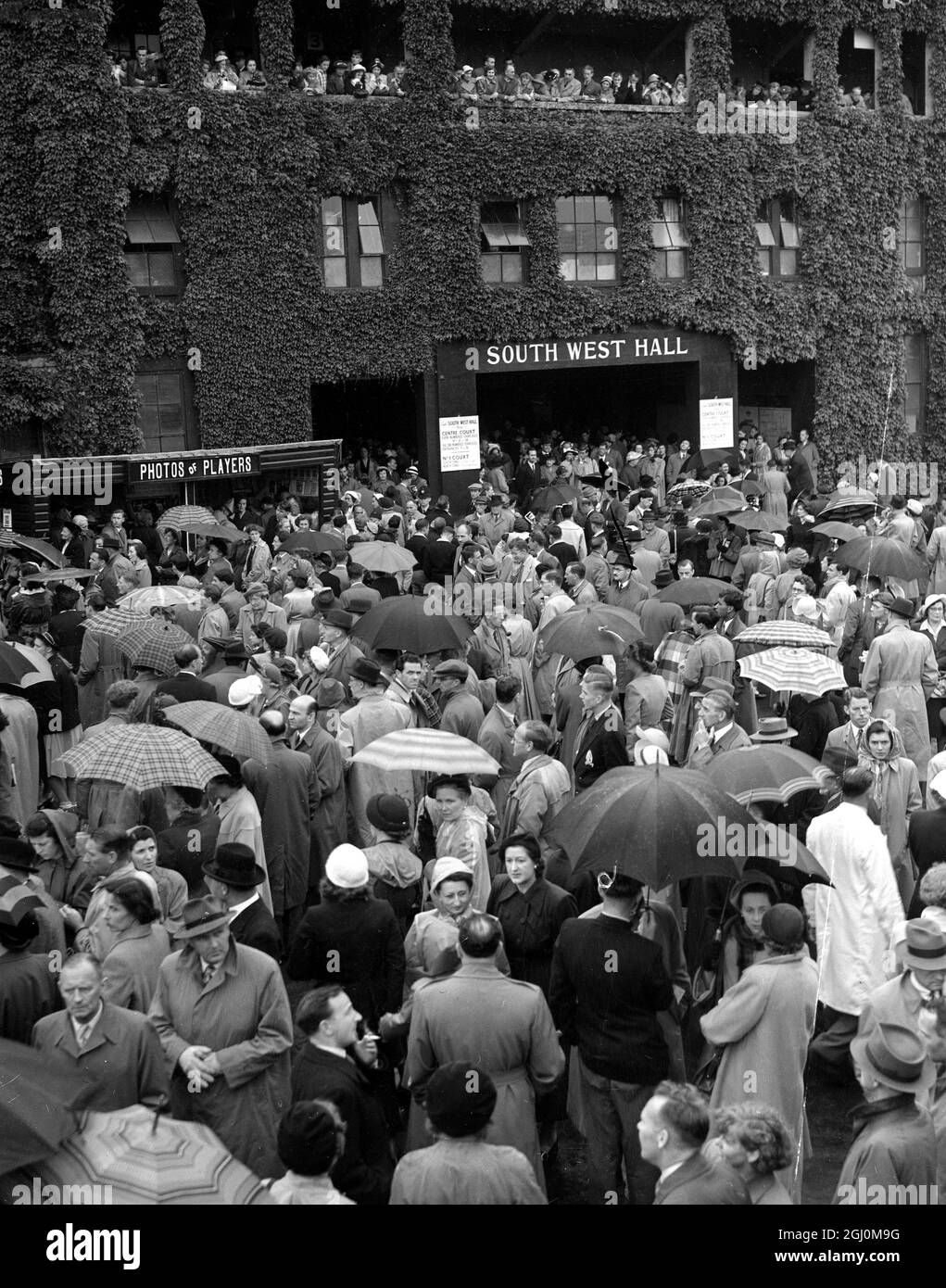 Regen hält an Wimbledon an Zuschauern werden Regenschirme gezeigt, die auf eine Pause bei Wetter warten. 26. Juni 1951 Stockfoto