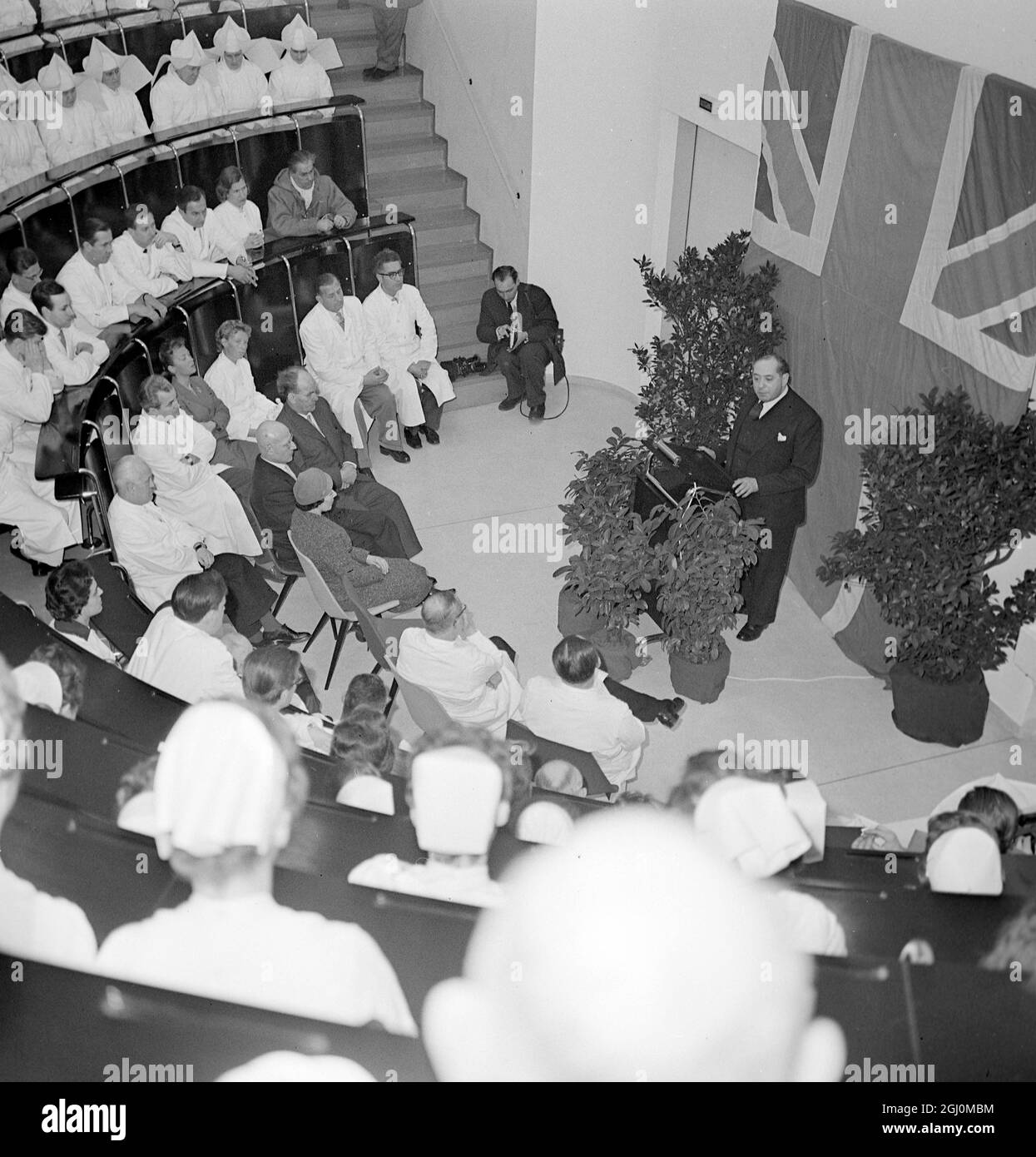 Oberbürgermeisterin Leslie Lever aus Manchester, England, spricht mit Mitarbeitern des Münchner Krankenhauses hinter ihm Union Jack-Fahne an der Wand des Auditoriums in Deutschland 12. März 1958 Stockfoto