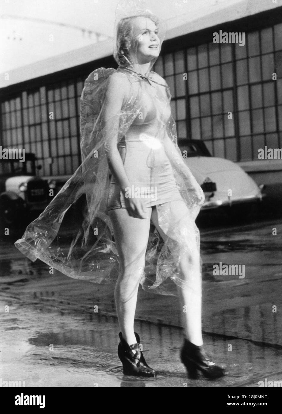 Marie Wilson, die Hollywood-Schauspielerin, schützt ihr modisches Badekleid mit diesem neuartigen Regenwetter-Kostüm aus Zellophan. Ein Paar Goloshes vervollständigt das Outfit Kaliforniens kürzlich heftige Regenfälle inspirierten das neue Kostüm. 1936 Stockfoto