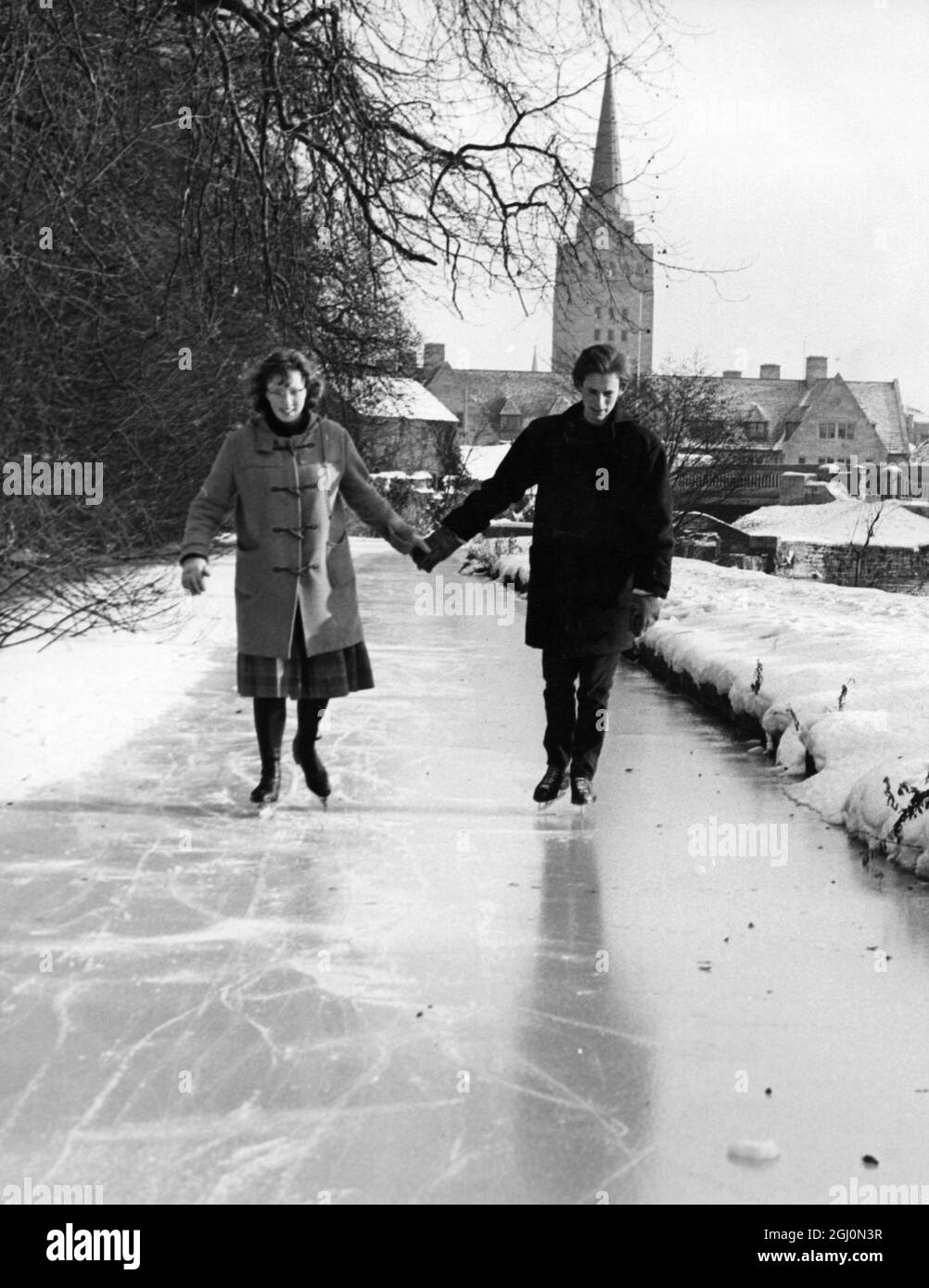 Studenten in Oxford profitieren von dem gefrorenen Fluss und Kanal, um die angebotenen natürlichen Schlittschuhmöglichkeiten zu genießen. Studets schicken nach Hause für ihre Schlittschuhe, und die örtlichen Sportgeschäfte und Second-Hand-Besucher treiben einen regen Handel mit Wintersportgeräten. Foto zeigt: L-R Anna Evans , 20 Jahre und Peter Haxroth , 21 Jahre , zwei der Oxford-Studenten, die am 18. Januar 1963 auf dem Kanal laufen Stockfoto