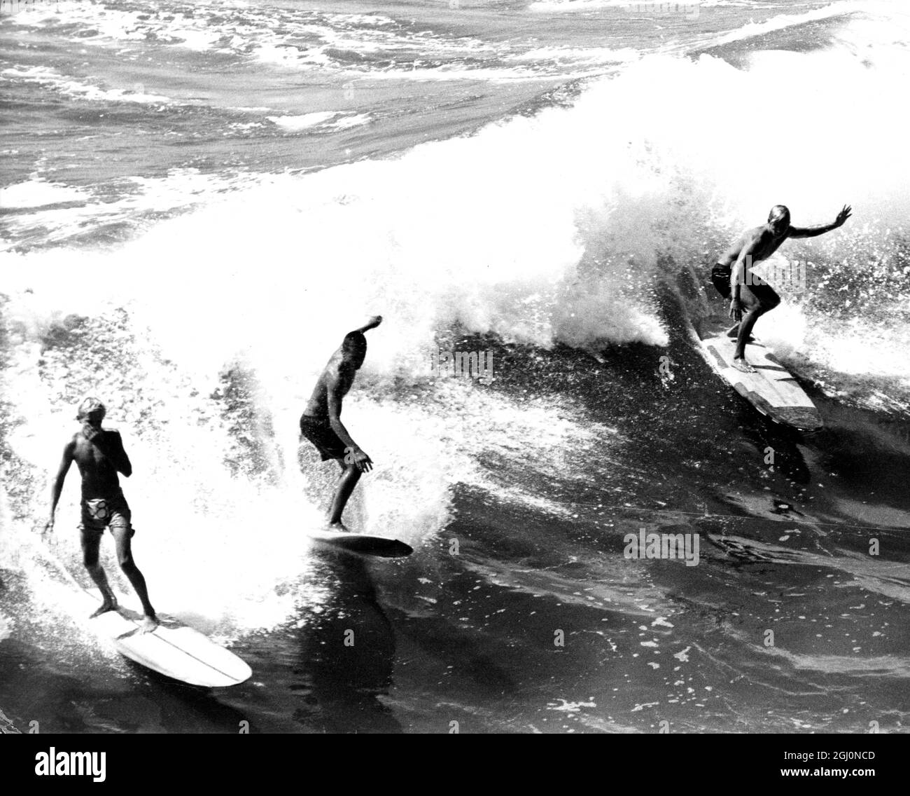Surfer reiten eine Welle in die Küste. 60er Jahre Stockfoto