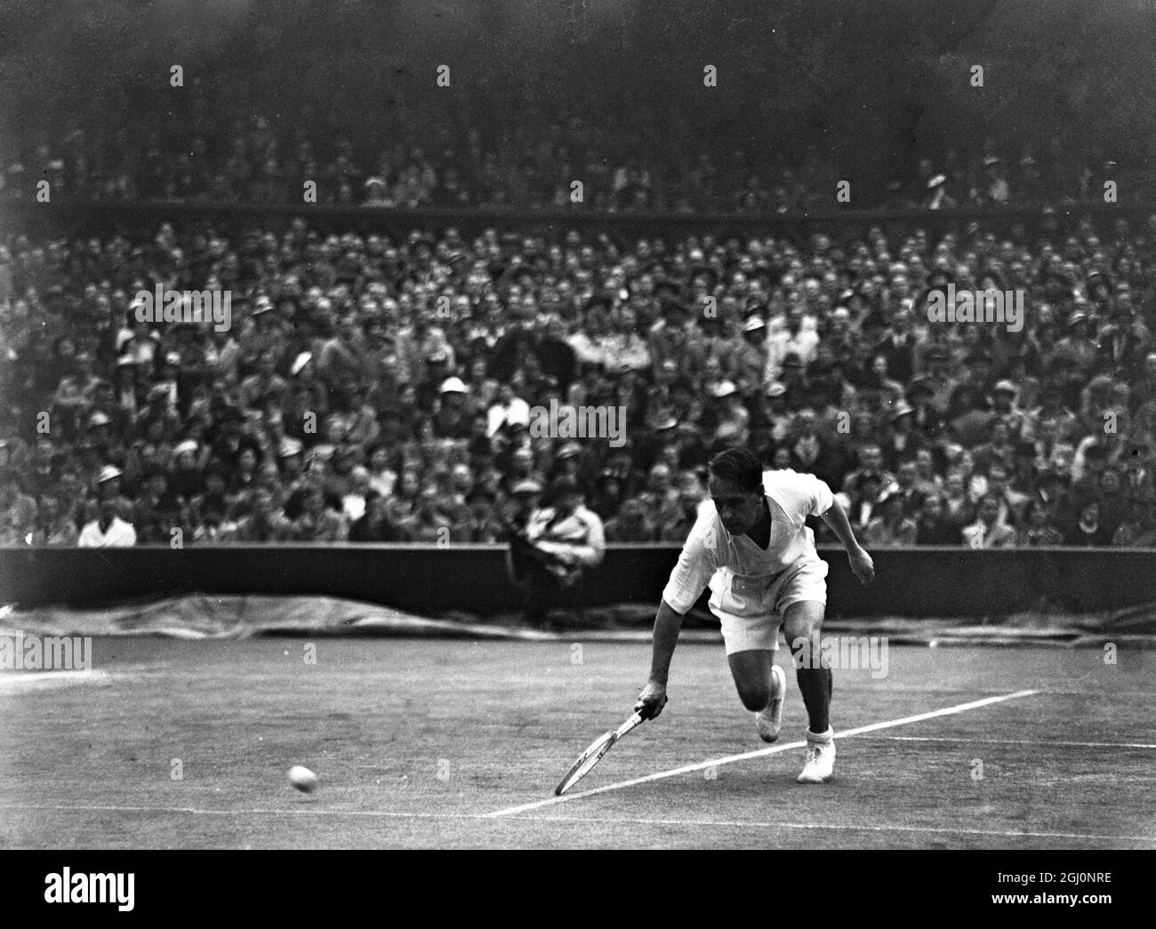 Fred Perry traf Adrian Quist aus Australien im Einzel der Davis Cup Challenge, die zwischen England und Australien in Wimbledon, England, führte. Regen gestoppt spielen mehrere Male . Das Foto zeigt, wie Quist während des Spiels einen Tiefschlag abgeschossen hat. 25. Juli 1936 Stockfoto