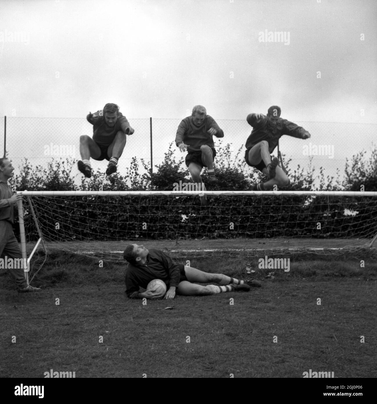Arsenal-Torwart Jim Furnell (am Boden) beobachtet als Teamkollegen (von links nach rechts) Joe Baker , George Eastham und Geoff starken Sprung in Richtung der Miniatur-Torhüter während des Trainings für den Start der Fußballsaison 1964-1965 . 19. August 1964 Stockfoto