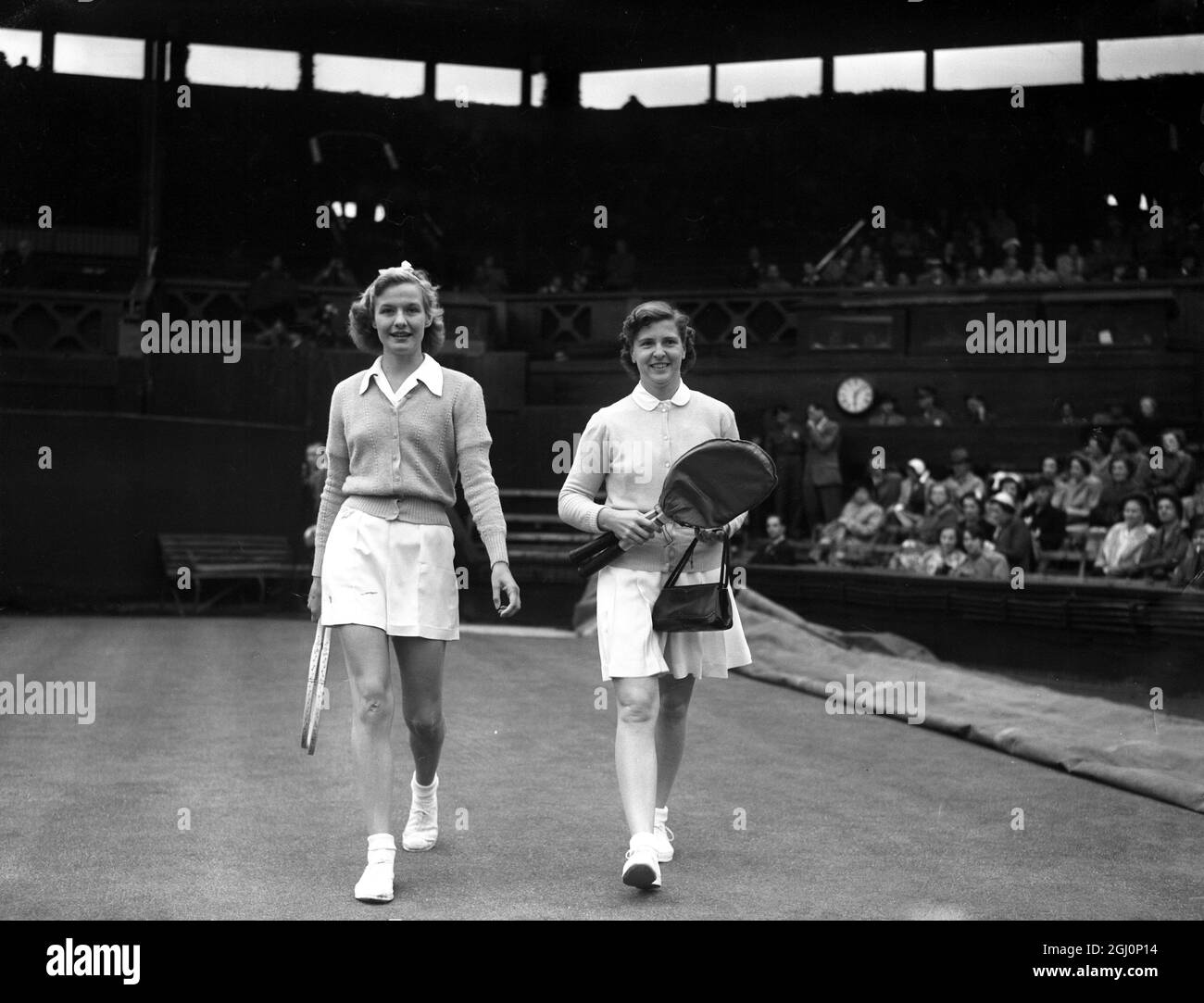 Frau A J Mottram aus Großbritannien (links) und Frau W du Pont (rechts) aus den Vereinigten Staaten gehen auf den Mittelplatz des All England Clubs für ihr Spiel in der ersten Runde der Ladies' Single Tennis Championship in Wimbledon in London. Mrs du Pont hat das Spiel gewonnen : 6 - 3 6 - 4 . Juni 1951 Stockfoto