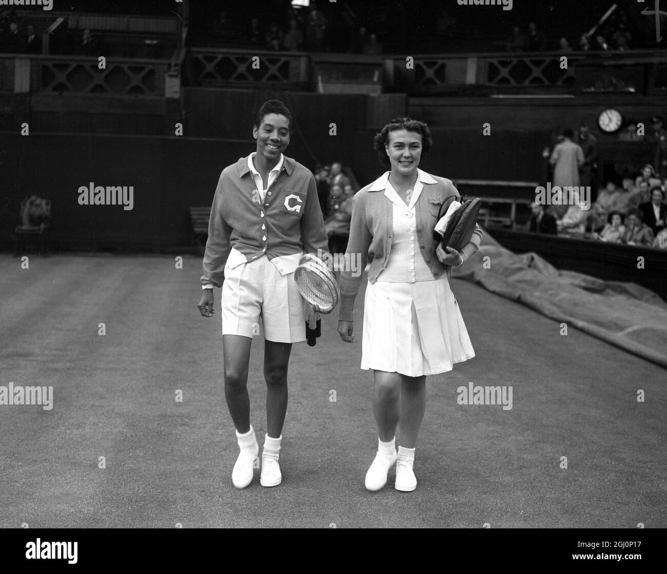 Die schwarze amerikanische Tennisspielerin, Miss Althea Gibson und ihre Gegnerin, die britische Miss Patricia ward, betreten den Platz für ihr Spiel bei den Wimbledon Tennis Championships in London. 1951 Stockfoto