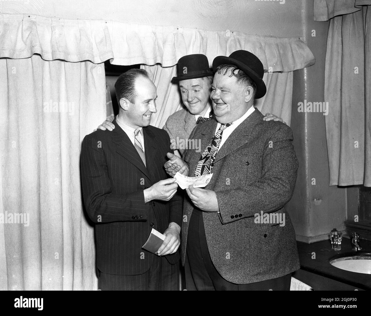 Edward Cross aus Aberdeen flog nach London, um die Rekorddividende von £61 456 für den Fußball-Pool zu sammeln. Mr Cross wurde von Stan Laurel und Oliver Hardy im Palladium Theatre in London überreicht, die sich eine Auszeit von ihrer persönlichen Auftritt-Tour durch Großbritannien genommen haben. 26. März 1947 Stockfoto