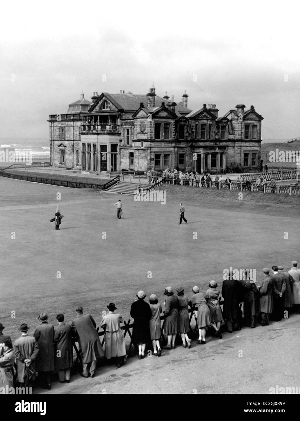St Andrews , das Hauptquartier jedes Golfer Grey Clubhauses im Hintergrund, Spieler und Caddy auf dem Grün des 18. Lochs auf dem Old Course. Ein Turnier ist eins und die Galerie hält den Atem an und beobachtet den 1. oktober 1949 Stockfoto