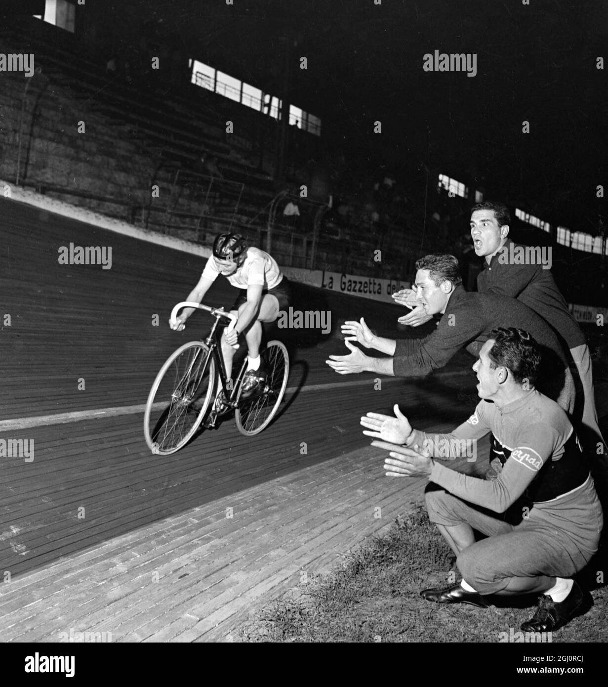 Mailand, Italien: Drei italienische Radfahrer jubeln und applaudieren, als die britische Radfahrerin Milly Robinson auf der Strecke auf dem Vigorelli Velodrome in Mailand Rennen fährt. Milly Robinson fuhr herum, um einen neuen 1-Stunden-Weltrekord für Frauen mit 39.718 km und 80 Zentimetern aufzulegen. Dies war ihr drittes Album, das von Milly aufgenommen wurde, die von zwei Jagdfans, die gekommen waren, um ihren Versuch zu sehen, angefeuert wurde. 27. September 1958 Stockfoto