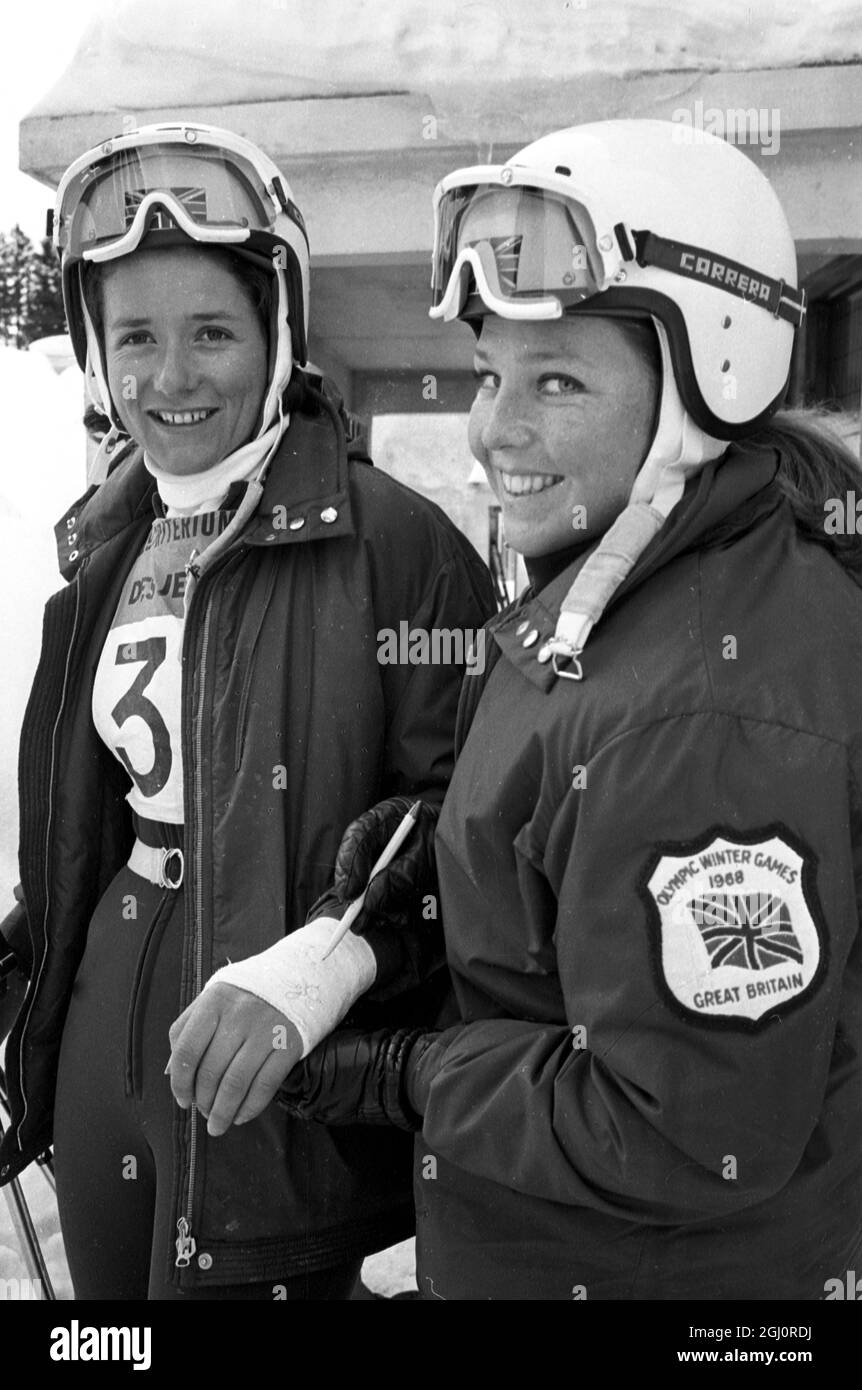 Diana Tomkinson vom britischen Olympia-Ski-Team lächelt, als Teamkollege Gina Hathorn die Besetzung, die sie nach einem Trainingsunfall in Grenoble, Frankreich, auf ihr gebrochenes Handgelenk gelegt hatte, autograpiert. 8. Februar 1968 Stockfoto