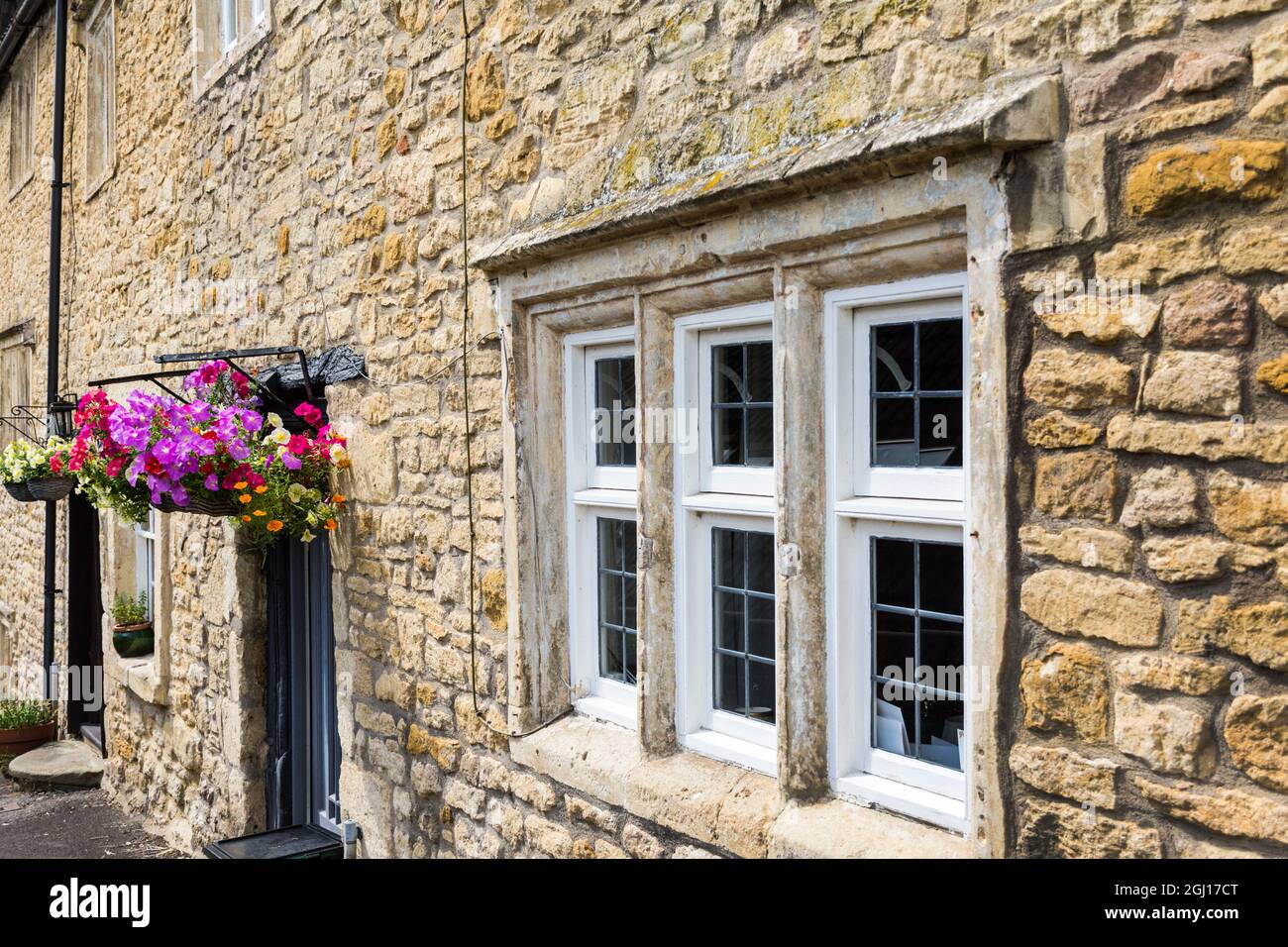 Mullionfenster und Blumenkörbe auf denkmalgeschütztem Haus in Batheaston, Somerset, Großbritannien Stockfoto