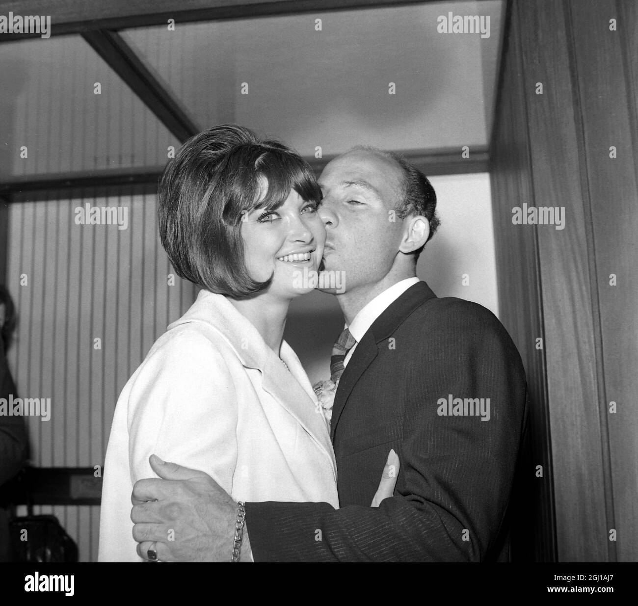 25. JUNI 1964 Stirling Moss küsst seine neue Braut, die ehemalige Miss Elaine Barberino, eine New Yorker Sekretärin, heute Nachmittag in ihrem Haus in Mayfair. Das Paar hatte heute eine geheime Standeshochzeit in der Kanzlei in den Dörfern von Bughamsted. London, England. Stockfoto