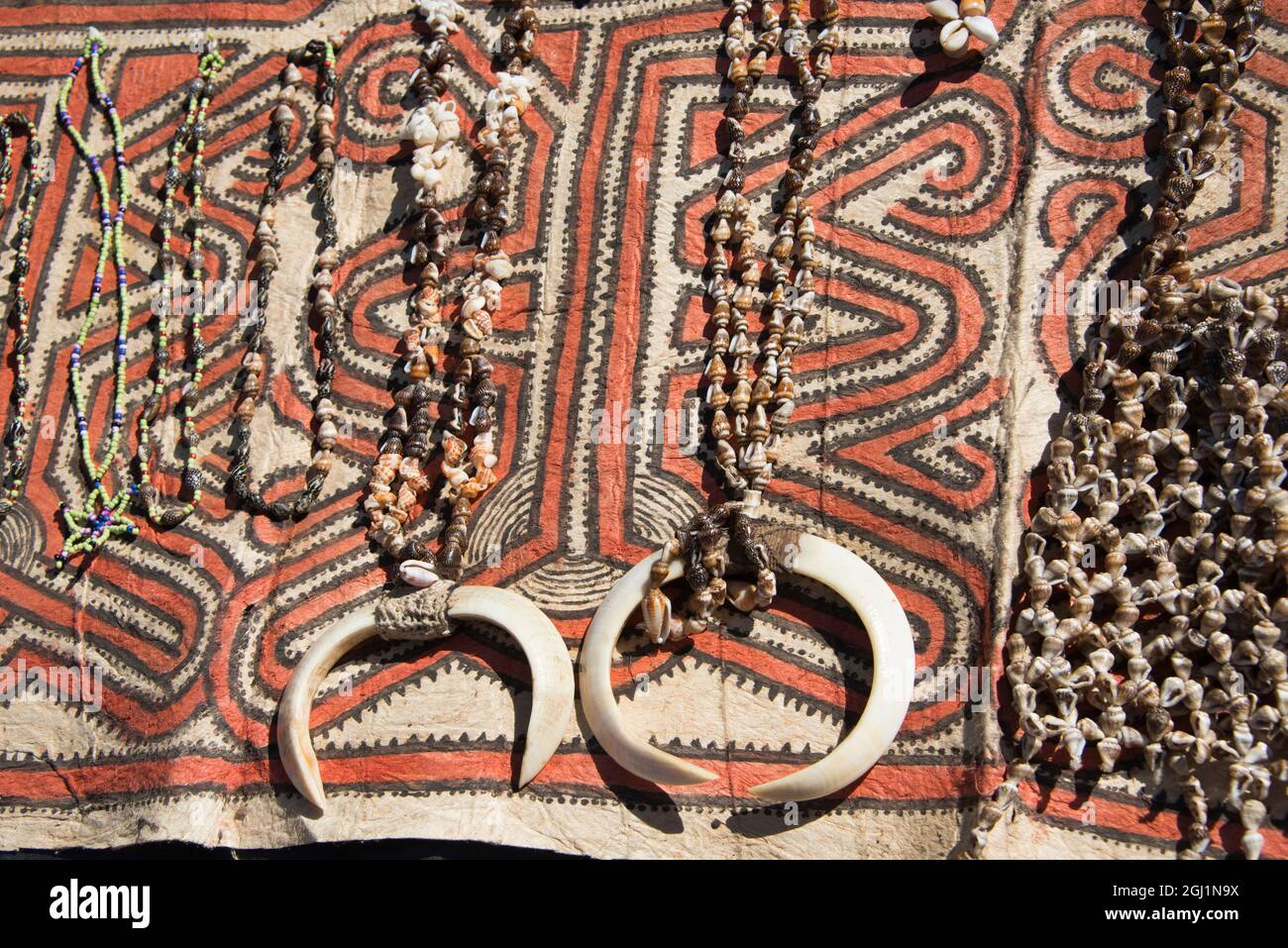 Papua-Neuguinea, Tufi. Muschelhalsketten mit Wildschweinzähnen auf traditionellem, handgefertigten Tapa-Tuch, hergestellt aus dem Maulbeerbaum aus Papier, handbemalt mit Natur Stockfoto