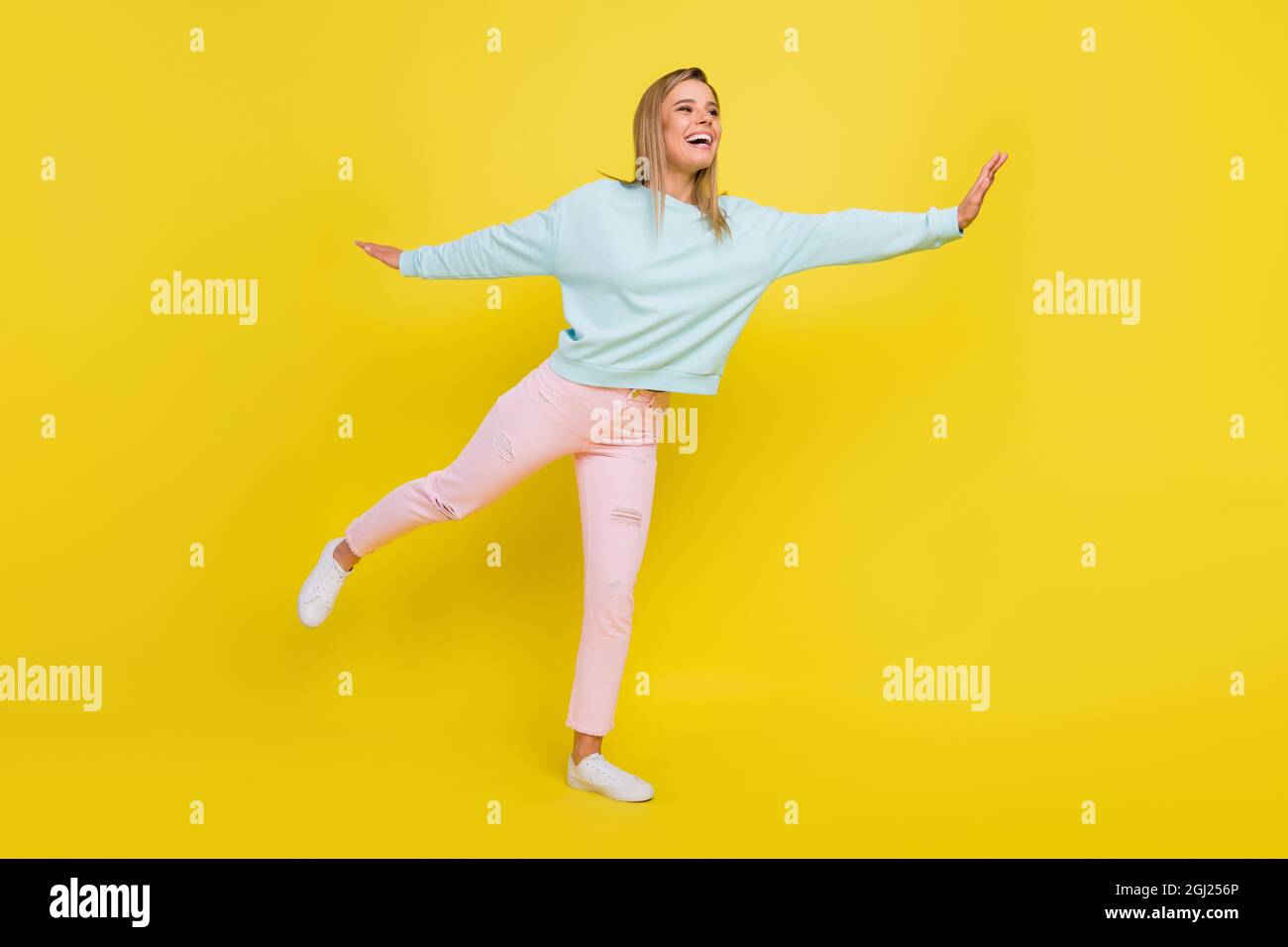 In voller Länge Körpergröße Ansicht der attraktiven froh fröhlich Mädchen fliegen Spaß isoliert über hellen gelben Hintergrund Stockfoto