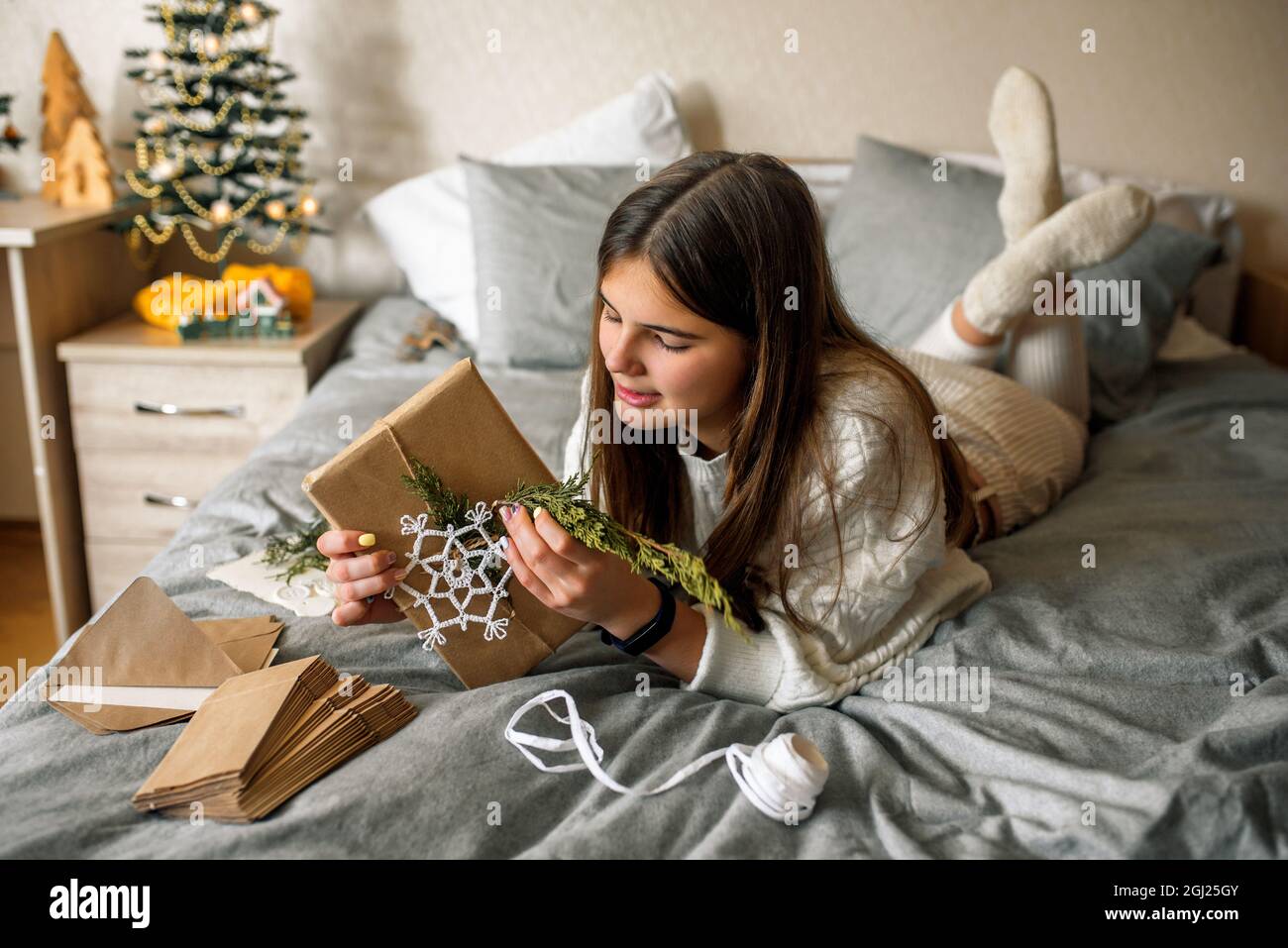 Mädchen Verpackung Geschenke mit Weihnachtsdekoration.Geschenk in einer Box, ein Brief in einem Handwerk Umschlag. Stockfoto
