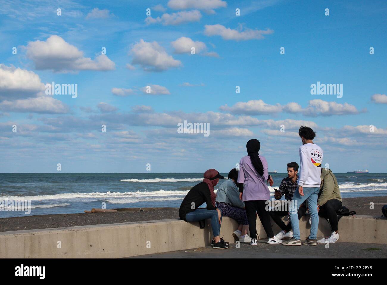 Gemischte ethnische Menschen am Meer, die Gespräche führen. Lebensentscheidungen. Weitere Lebenspläne. Stockfoto