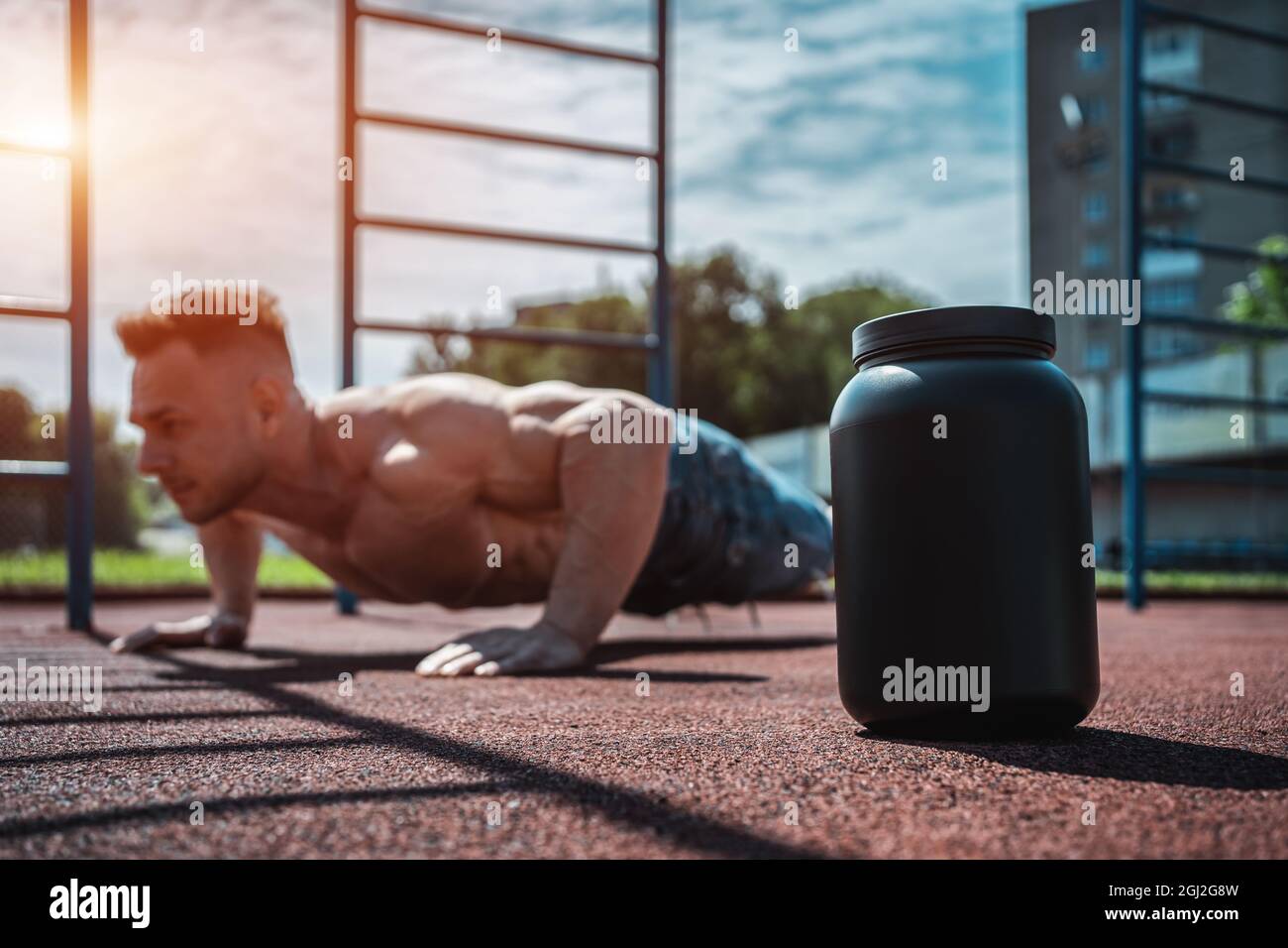 Protein-Molkengetränk in schwarzem Behälter und muskulösen Athleten trainieren im Freien Stockfoto