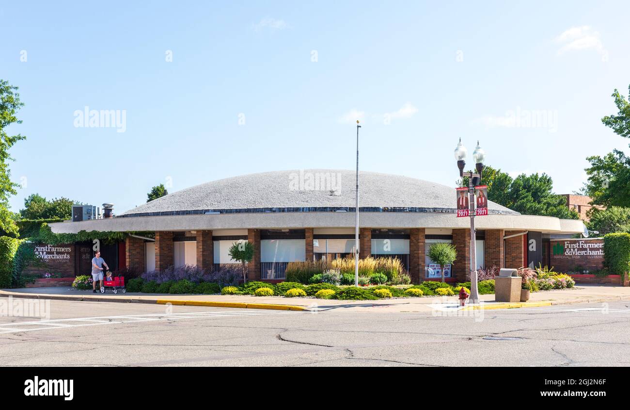 LUVERNE, MN, USA-21 AUGUST 2021: First Farmers & Merchants National Bank, Building and Signs. Mann, der kleines Kind im Wagen läuft. Stockfoto