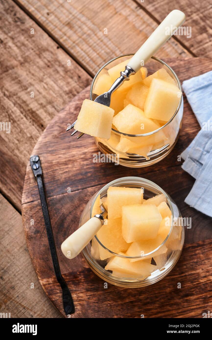 Melone. Stücke von frischer Melone für die Herstellung von Obst Dessert im Glas auf einem alten Holzhintergrund. Modell. Draufsicht. Stockfoto