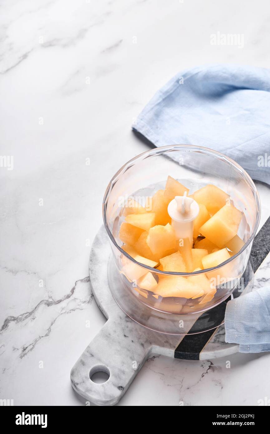 Melone. Stücke von Melone für die Herstellung von Obst Dessert im Mixer für die Herstellung von Saft oder richtige Ernährung auf Marmor weißen Hintergrund vorbereitet. Modell. Obere V Stockfoto