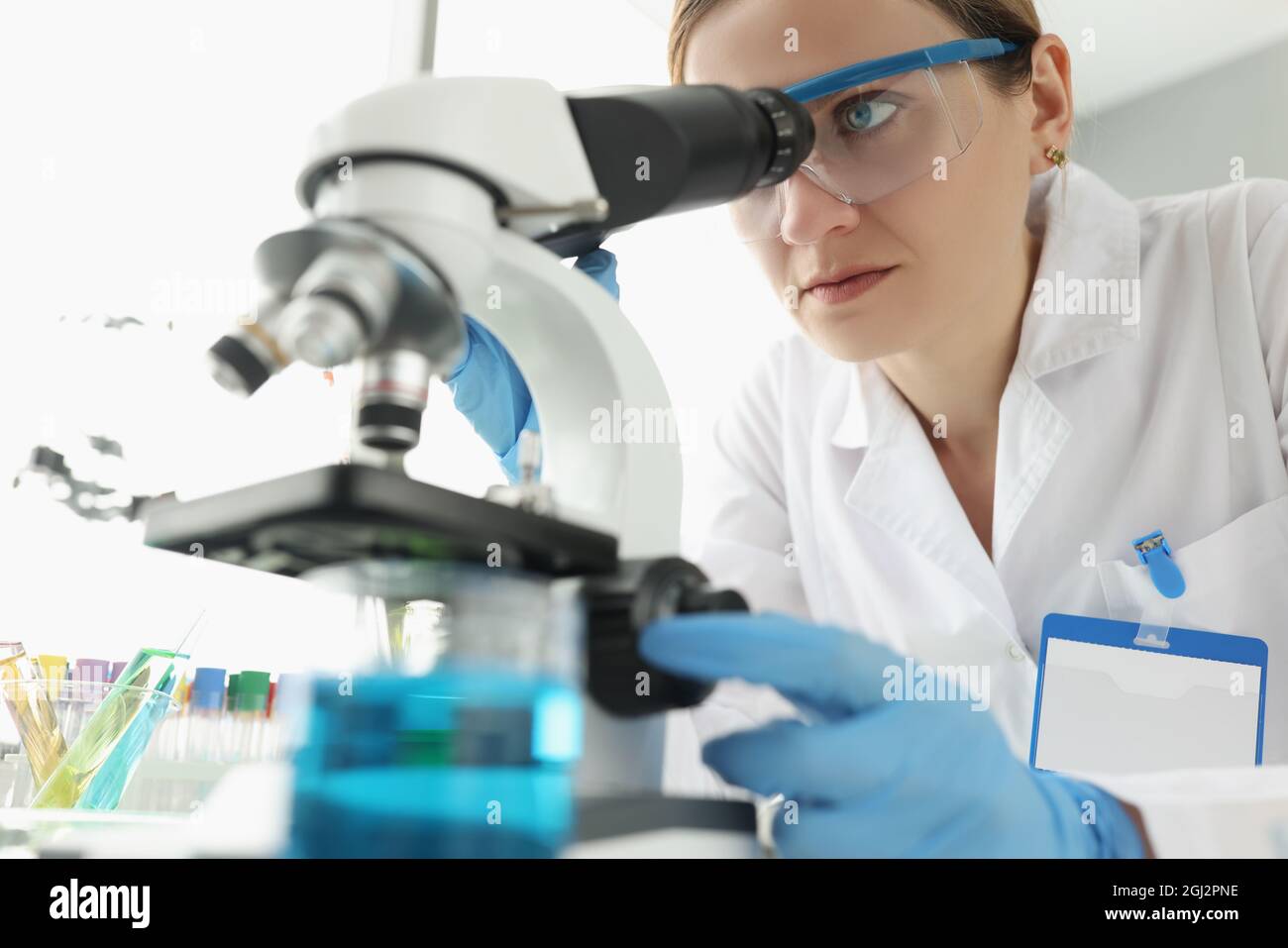 Porträt einer Wissenschaftlerin, die im Labor durch das Mikroskop schaut Stockfoto