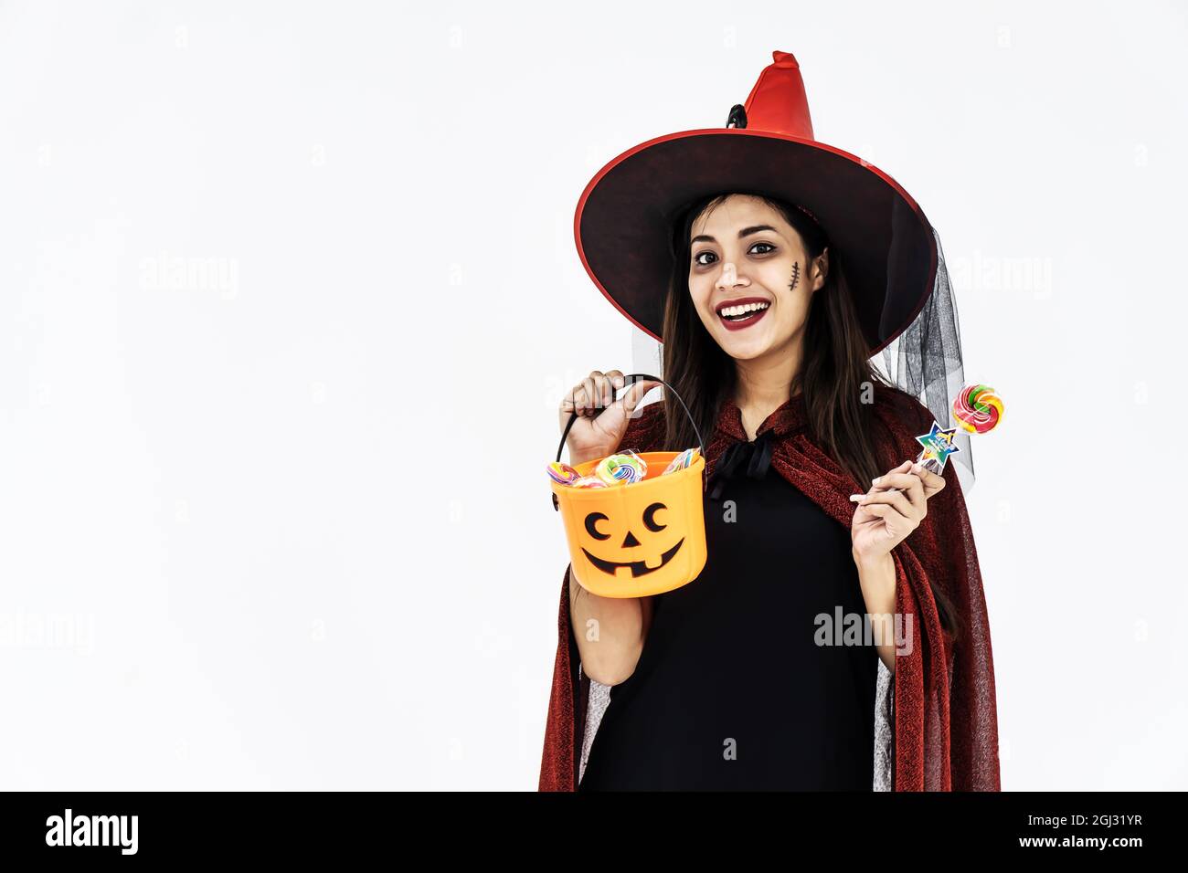 Schöne junge Frau in Hexenhut und kurzen Kleid mit Tank Orange und Lutscher Süßigkeiten Stockfoto