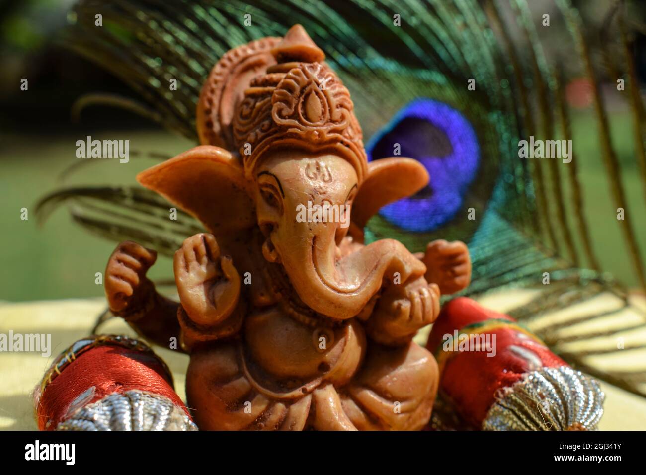 Schöner herr Ganesha Idol verehrt während Ganesh chaturthifest mit Pfauenfeder im Hintergrund. Sitzende Ganpati mit Kissen und Polstern Stockfoto