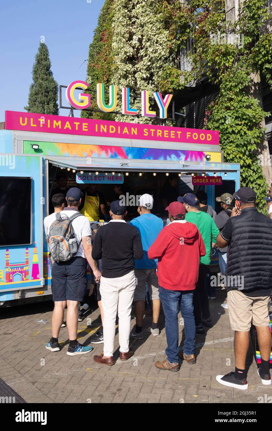 Multikulturelles Großbritannien; Menschen, die Street Food von einem Gully Indian Street Food Stall, The Oval, Kennington London, Großbritannien, kaufen, Beispiel für multikulturelles London Stockfoto