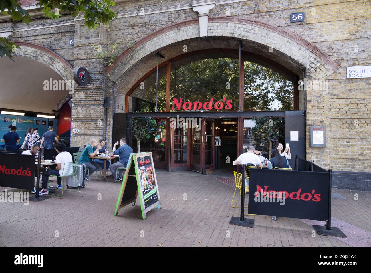 Nandos UK; Nandos Restaurant mit Leuten, die draußen essen, Vauxhall, London UK Stockfoto