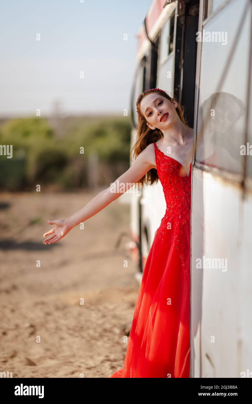 Junge schöne Frau in rotem Kleid ist mit Bus oder Zug unterwegs. . Hochwertige Fotos Stockfoto