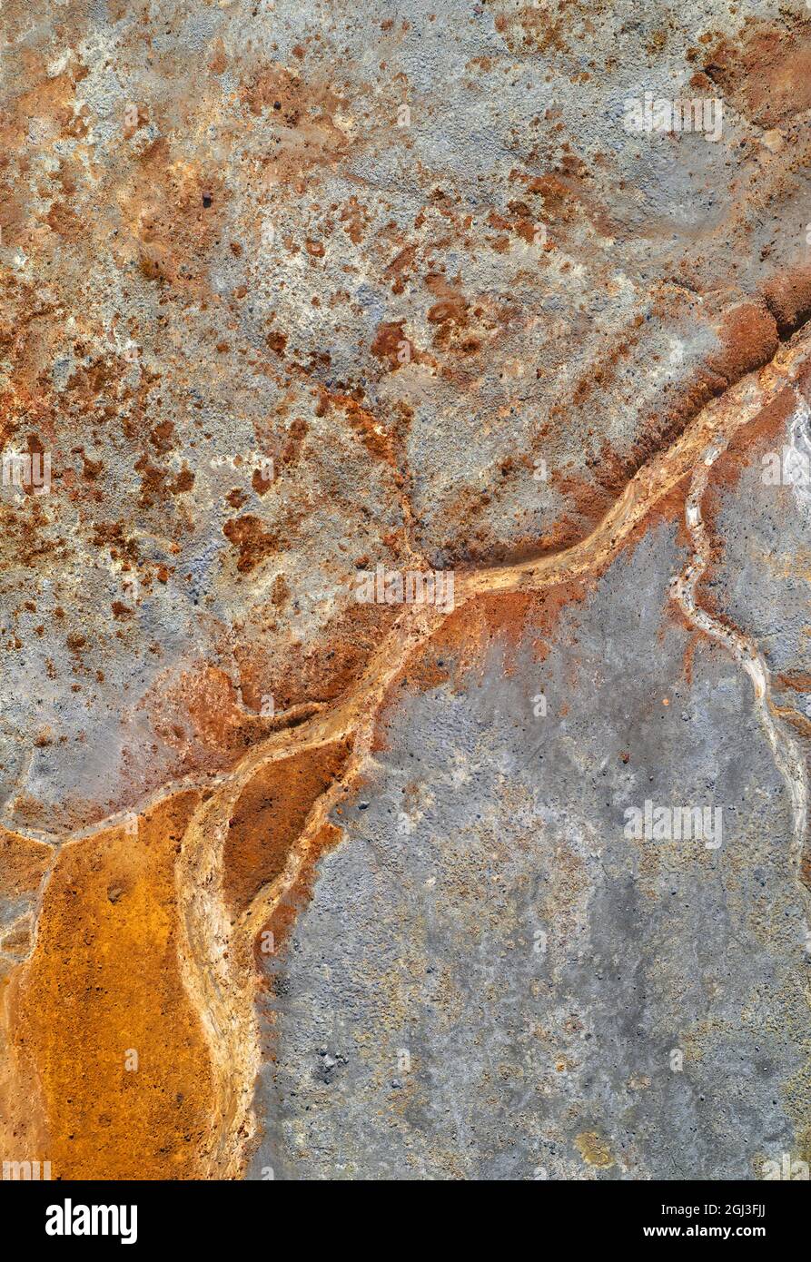 Trockener rostiger Flussboden über grauen Bergrückständen, vertikale Struktur des sauren Minenabflusses Stockfoto