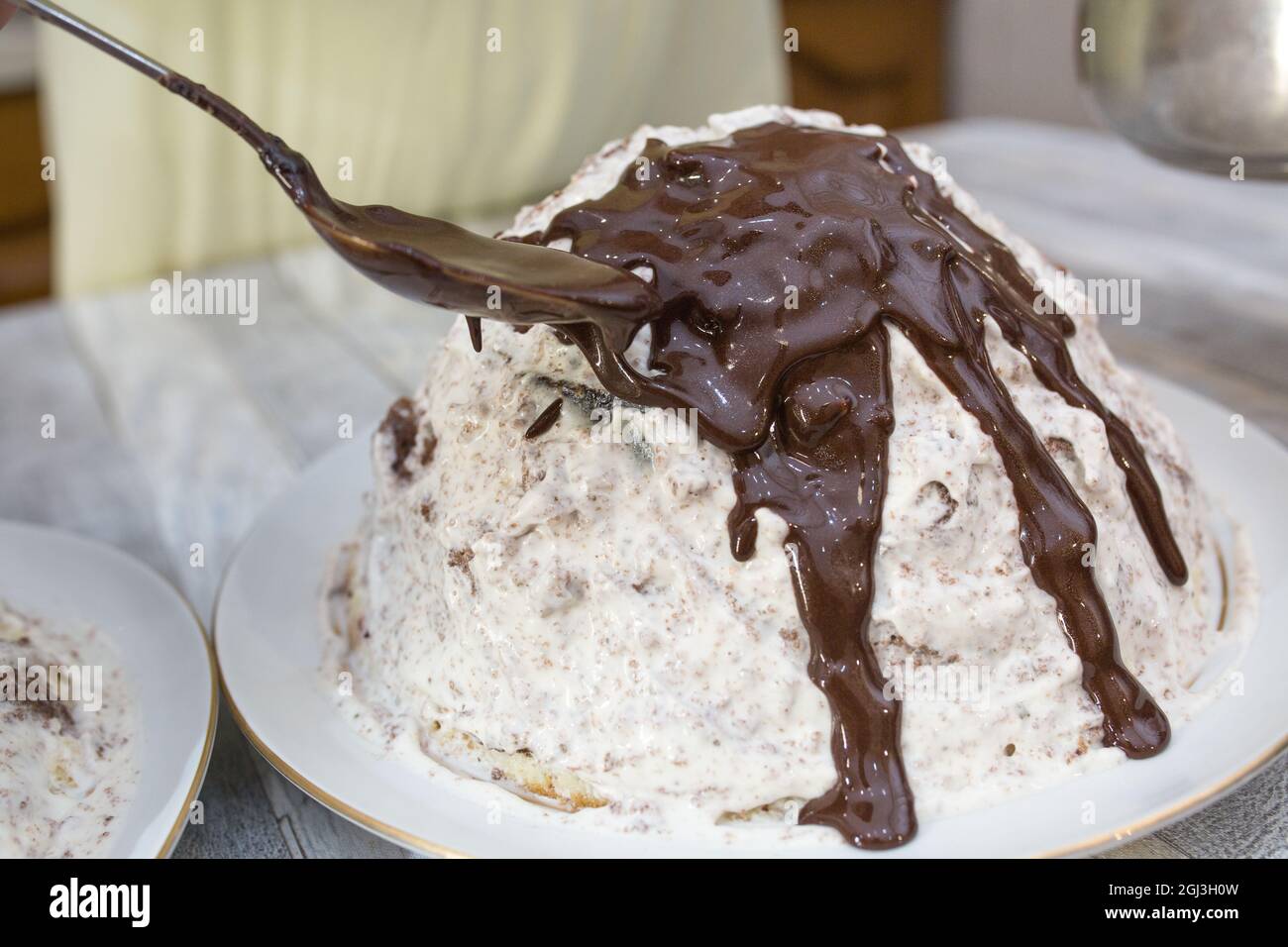 Kuchenherstellung. Vorbereiteter Schokoladenkuchen mit saurer Creme wird mit Schokoladeneier gegossen. Schritt für Schritt Rezept für Schokoladenkuchen. Serie. Backen von CO Stockfoto