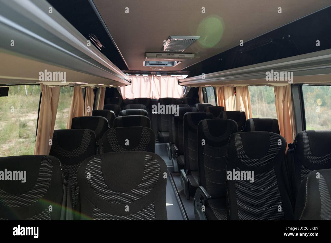 Komfortabler Bus mit Deckenfächern unter Stoffsitzen und Vorhängen an Fenstern Stockfoto