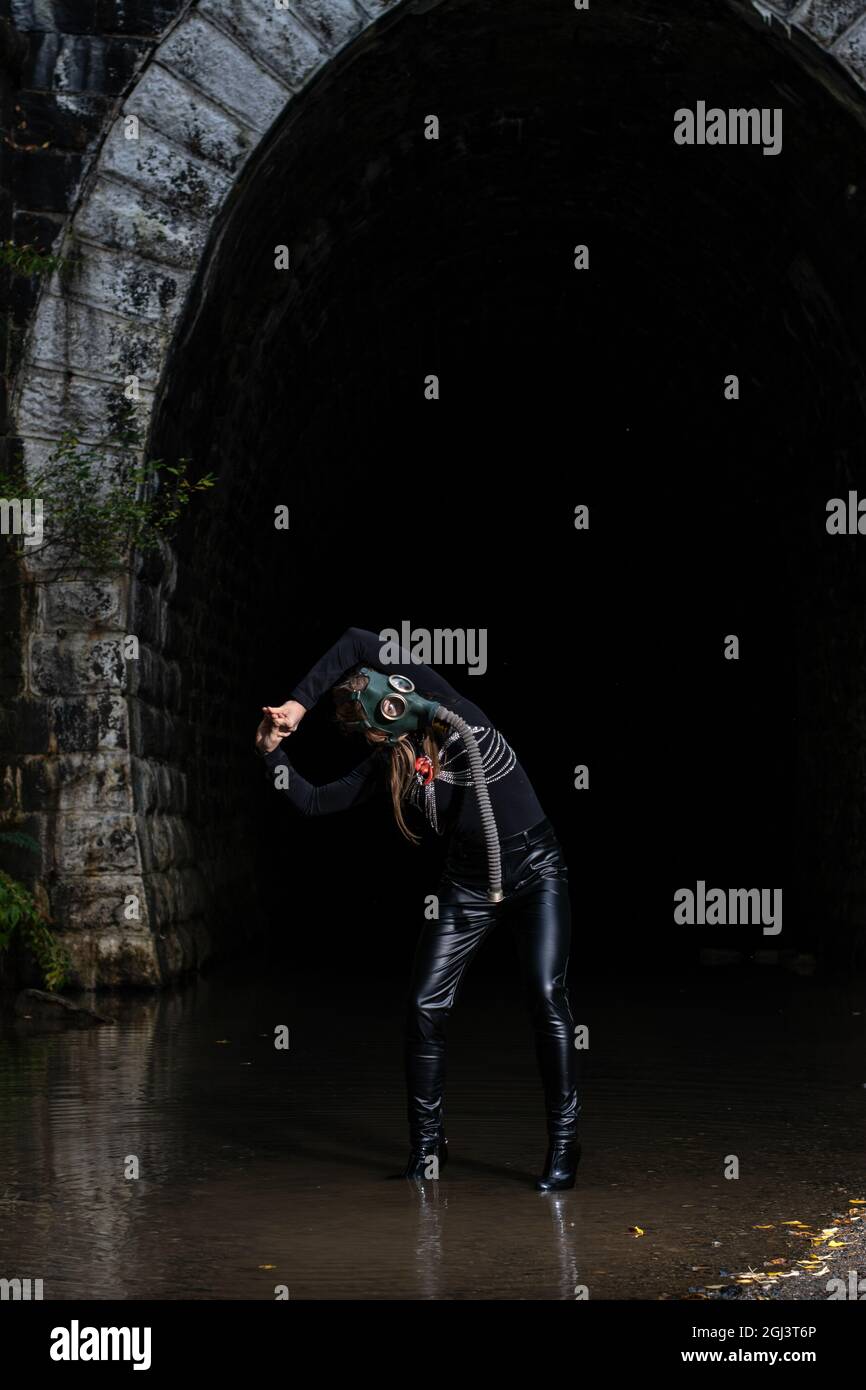 Eine Frau in einem schwarzen Anzug und einer Gasmaske mit einem Maschinengewehr in den Händen Stockfoto