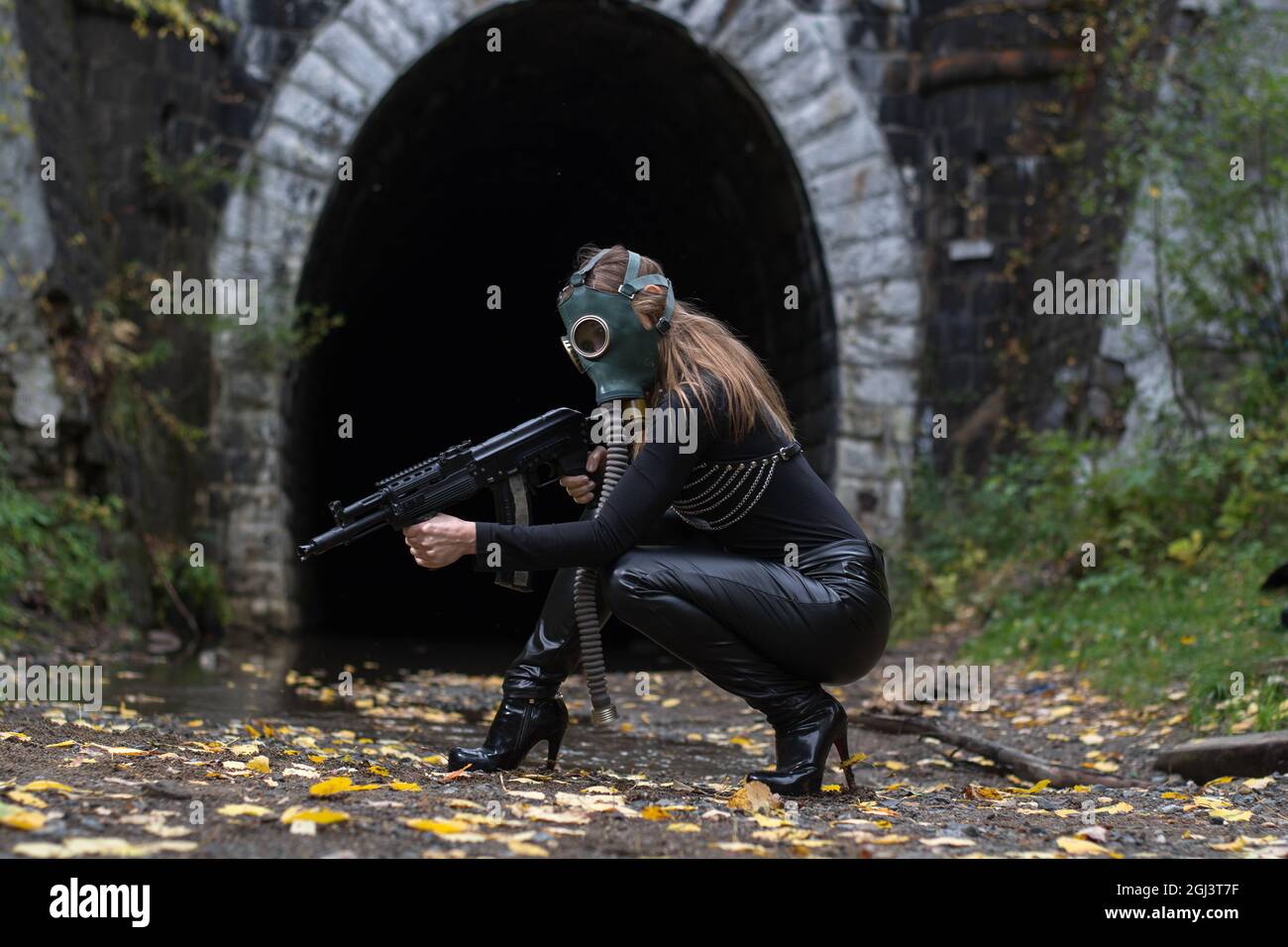 Eine Frau in einem schwarzen Anzug und einer Gasmaske mit einem Maschinengewehr in den Händen Stockfoto