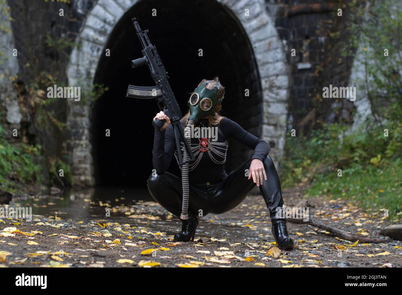 Eine Frau in einem schwarzen Anzug und einer Gasmaske mit einem Maschinengewehr in den Händen Stockfoto