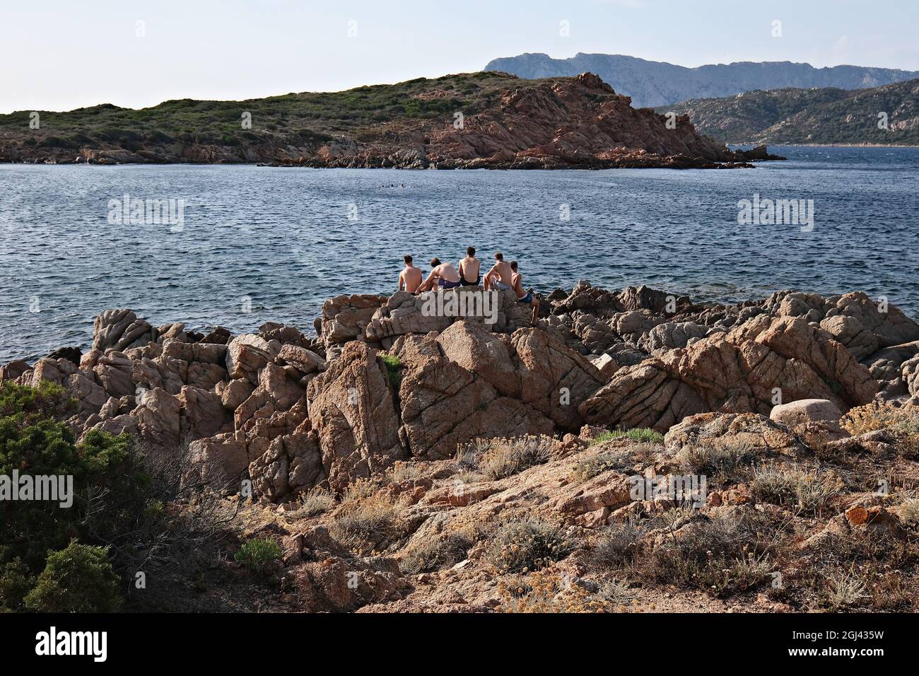 Eine Gruppe von Jungs, die bei Sonnenuntergang auf den Felsen sitzen Stockfoto