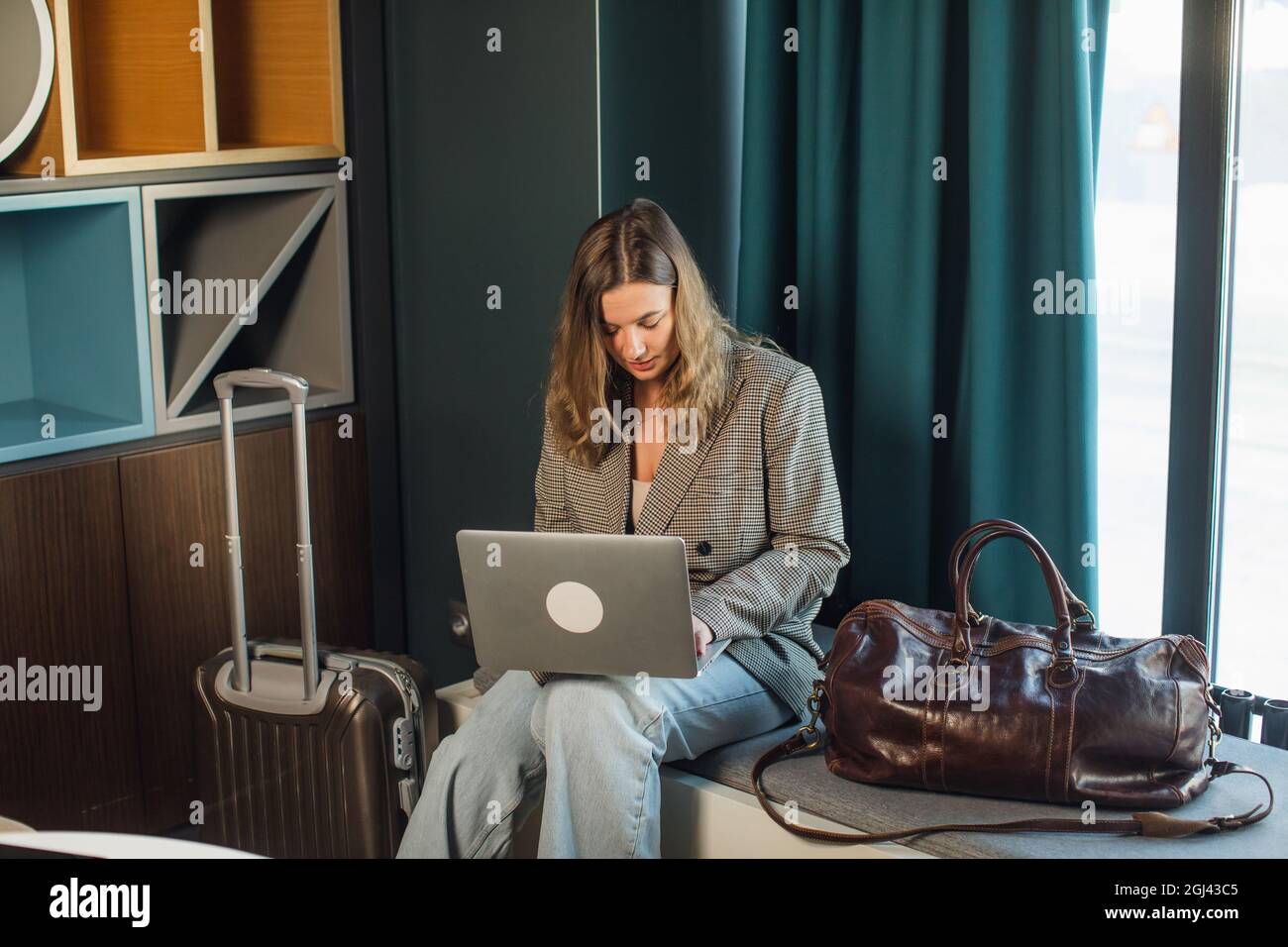 Junge Texterin, die Texte für das Posten von Artikeln auf Content-Websites mithilfe von Netbooks erstellt, während sie in Innenräumen Remote arbeitet Stockfoto