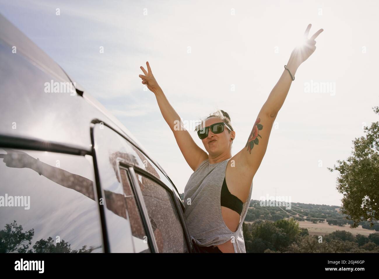 Mädchen, das aus dem Autofenster blickt und ihre Arme vor Glück hochgehoben hat. Reisekonzept und Lifestyle Stockfoto