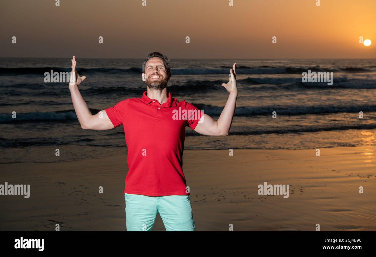 Glücklicher erfolgreicher Mann über dem Meer am Sonnenuntergang Sommerstrand, Erfolg Stockfoto