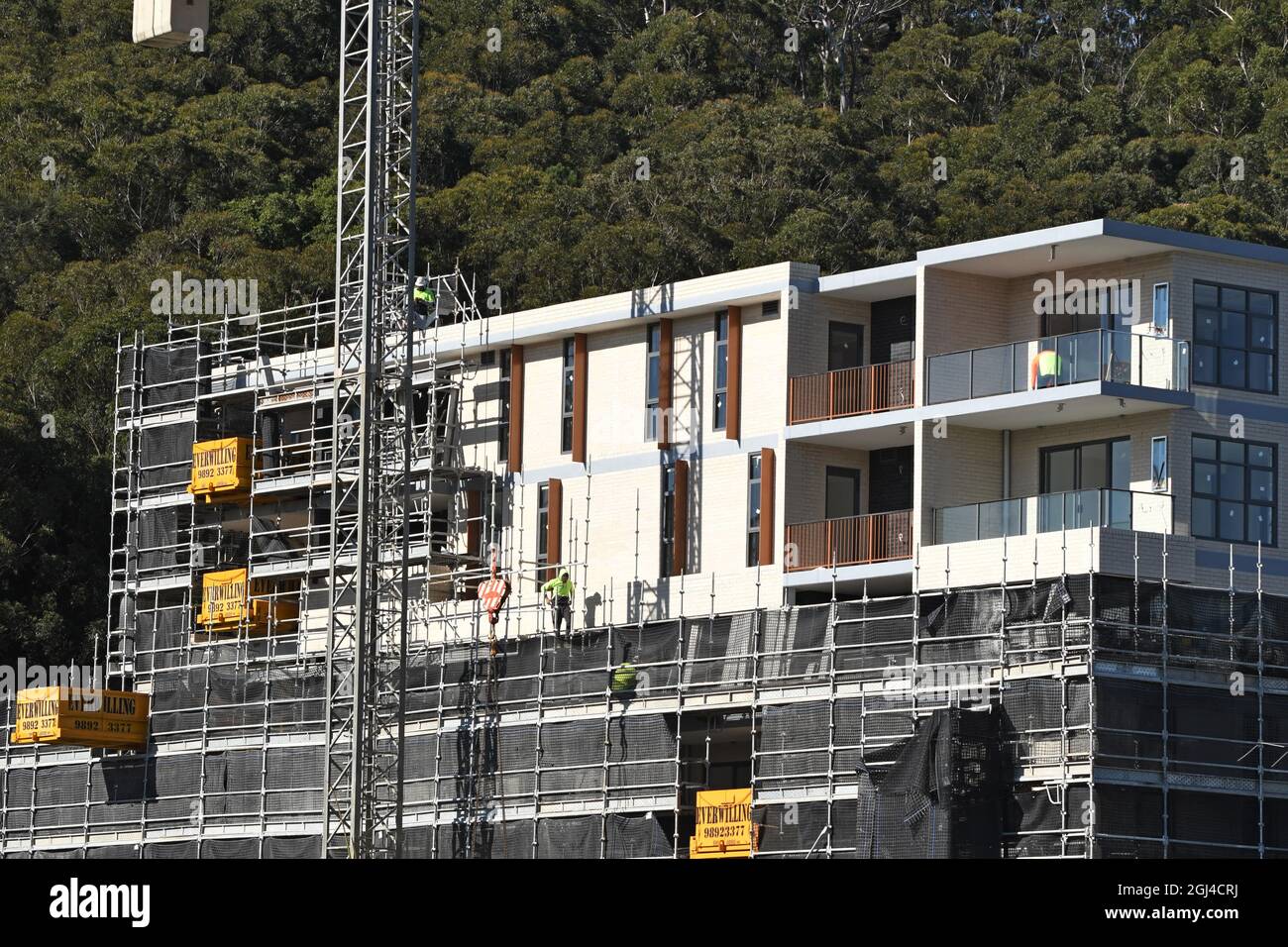 Gosford, NSW, Australien - 15. Juli 2021: Arbeiter demontieren Sicherheitsnetze und Gerüste in den nun fertiggestellten oberen Stockwerken des neuen sozialen Wohnungsbaus bei Stockfoto