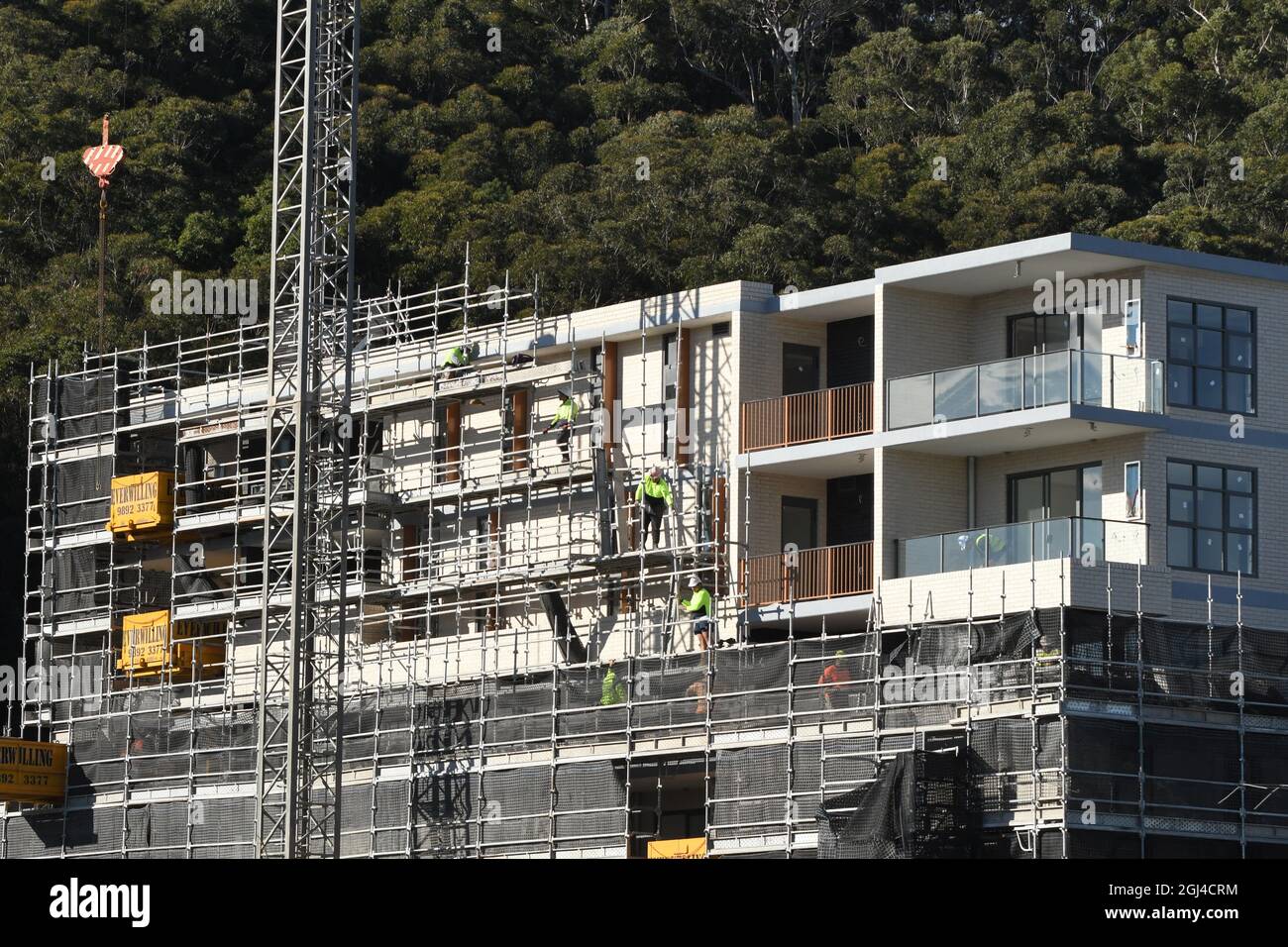 Gosford, NSW, Australien - 15. Juli 2021: Arbeiter demontieren Sicherheitsnetze und Gerüste in den nun fertiggestellten oberen Stockwerken des neuen sozialen Wohnungsbaus bei Stockfoto