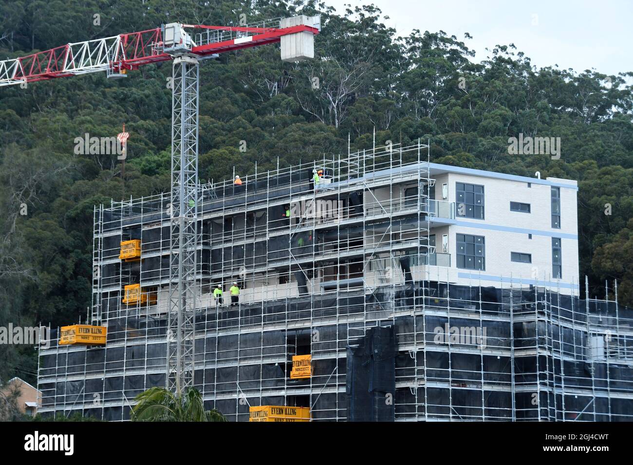 Gosford, NSW, Australien - 15. Juli 2021: Arbeiter demontieren Sicherheitsnetze und Gerüste in den nun fertiggestellten oberen Stockwerken des neuen sozialen Wohnungsbaus bei Stockfoto