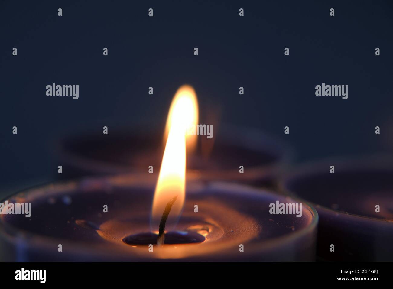 Brennende Kerzen.Kerzenflamme.Kerzen im Dunkeln einstellen.Religionssymbol. Kerzen Hintergrund.Blaue Kerzen auf blauem Hintergrund Stockfoto