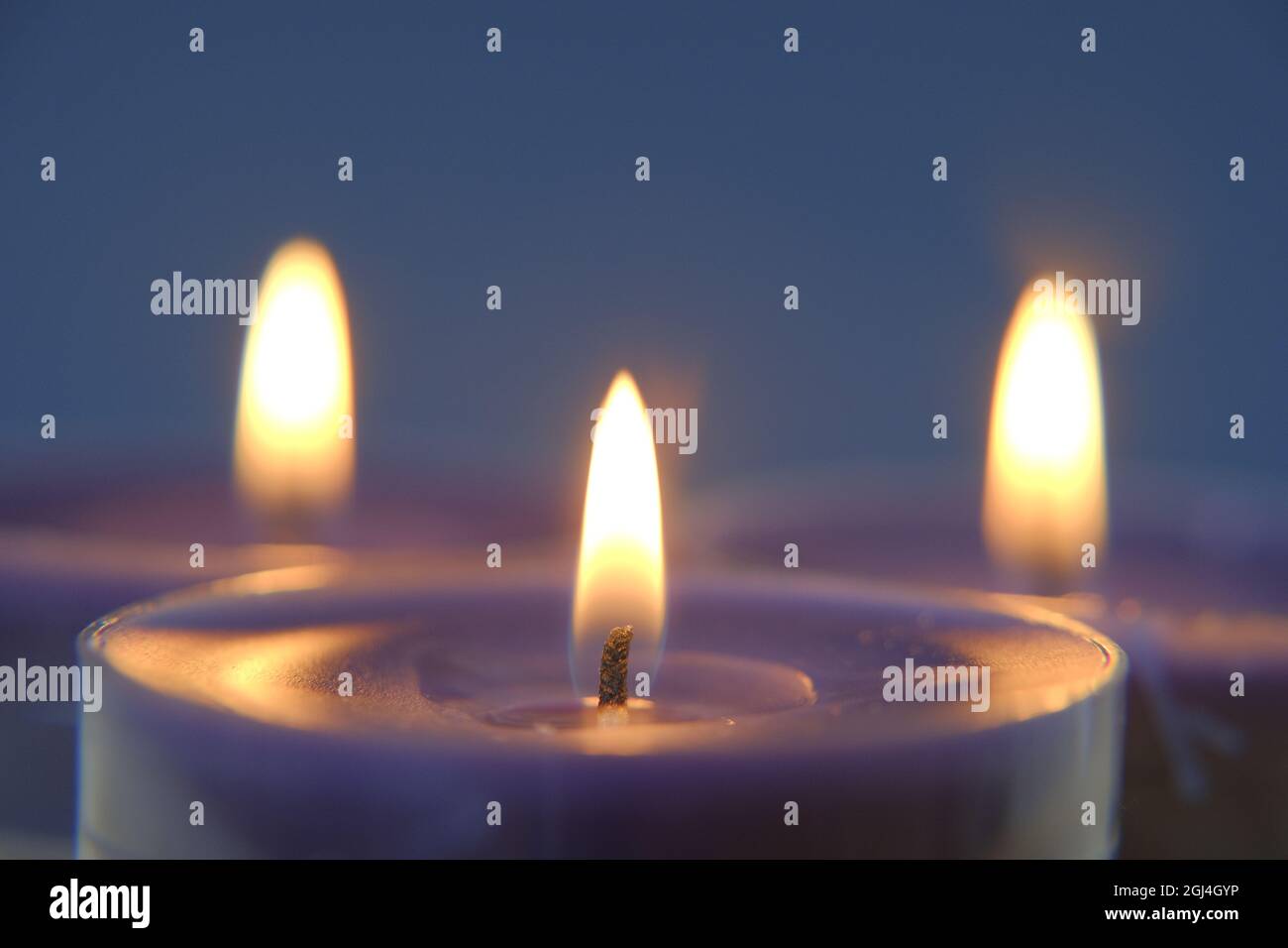 Brennende Kerzen.Kerzenflamme.Set von blauen und weißen Kerzen im Dunkeln.Religion Symbol. Kerzen Hintergrund.Blaue Kerzen auf blauem Hintergrund Stockfoto