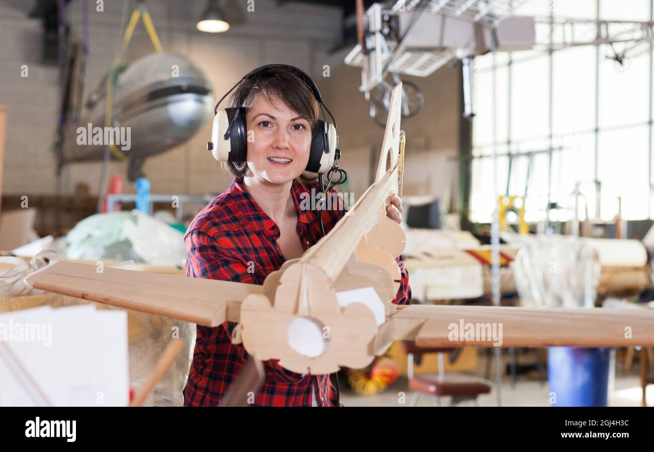 Glückliche Frau in Fliegerkopfhörern mit monoplaner Modell Stockfoto
