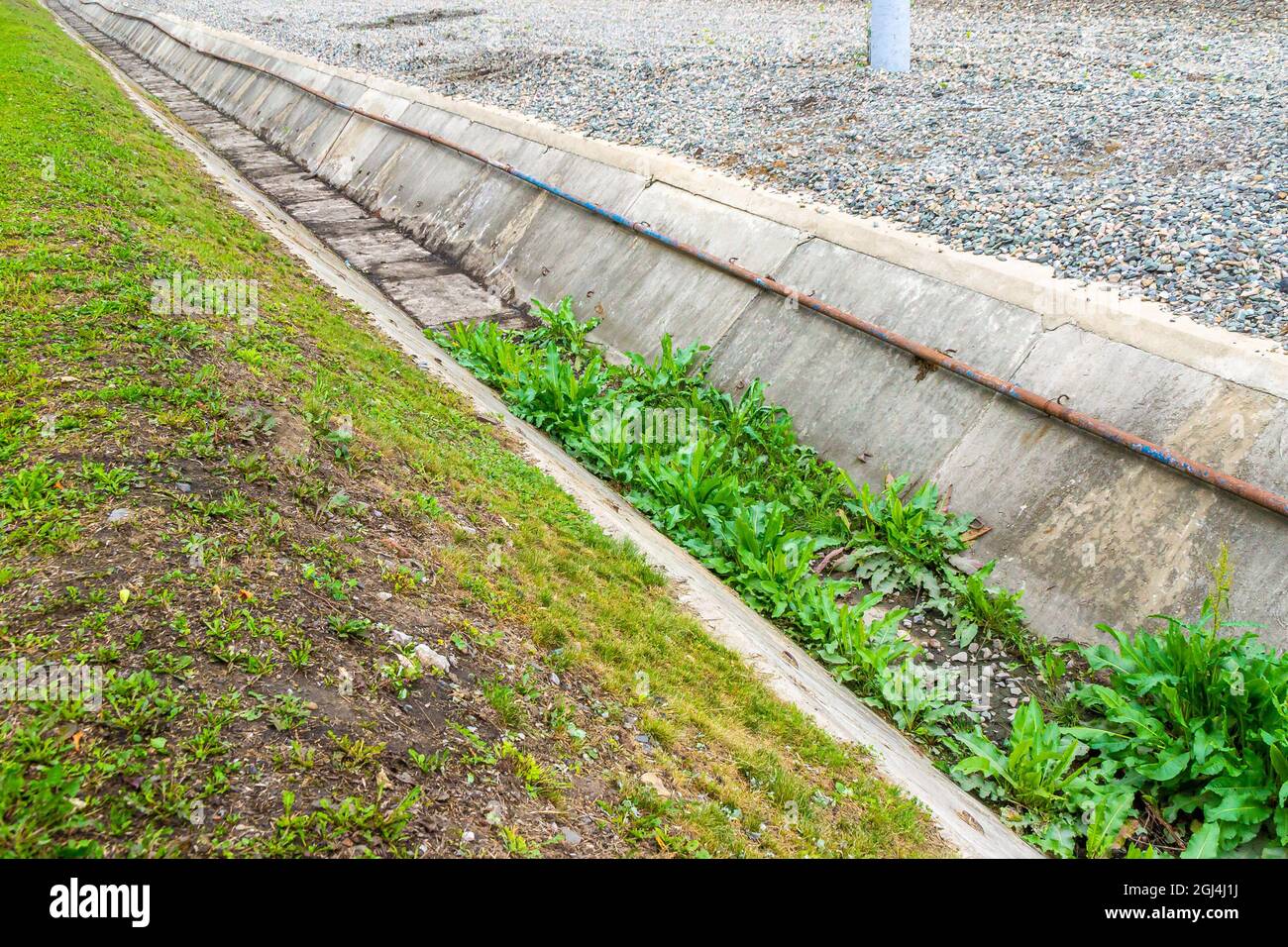 Der Industriekanal zur Ableitung von Regenwasser und zum Schutz vor Hochwasser wurde von dem Gras, mit dem es bewachsen war, zur Hälfte gereinigt Stockfoto
