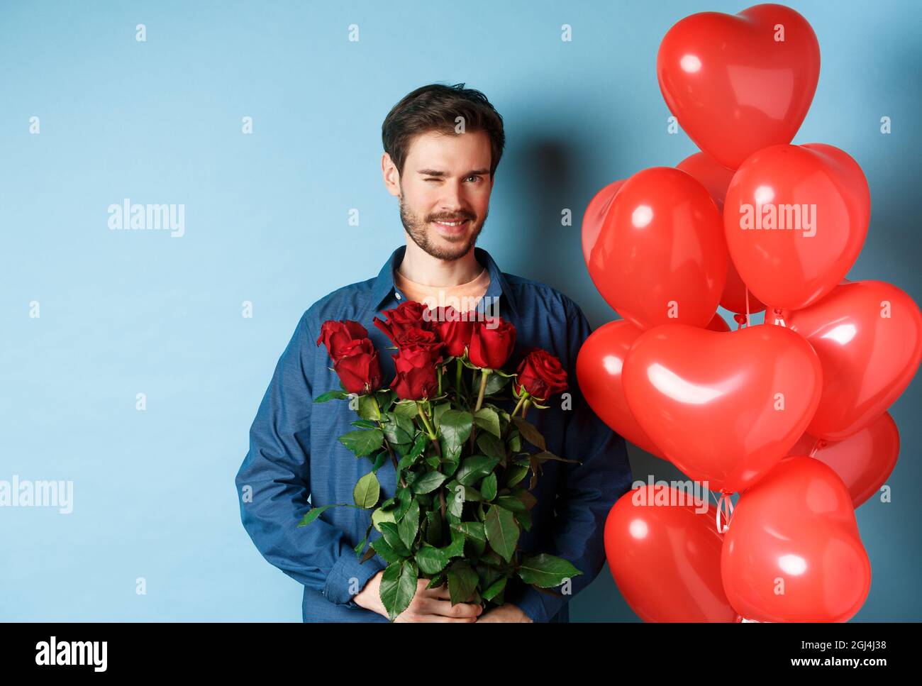 Romantischer Freund Winkend Und Lachelnd Halt Blumenstrauss Am Valentinstag Steht In Der Nahe Herz Ballons Fur Liebhaber Blauer Hintergrund Stockfotografie Alamy