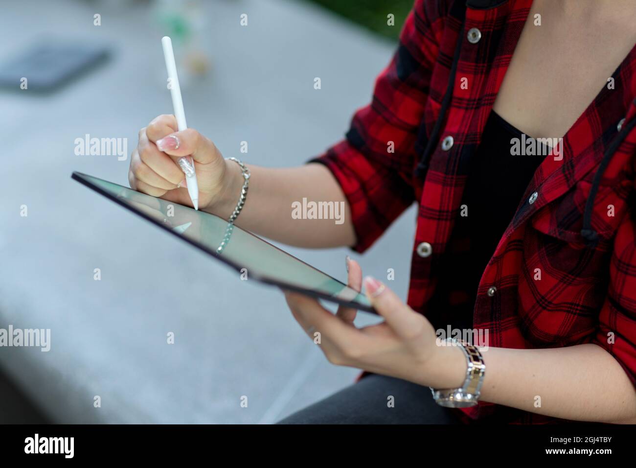Zugeschnittenes Bild von Hipster Mädchen mit digitalen Tablet mit Stylus-Stift, um digitale Kunstwerke zu schaffen, sitzen in der Stadt Straße Stockfoto