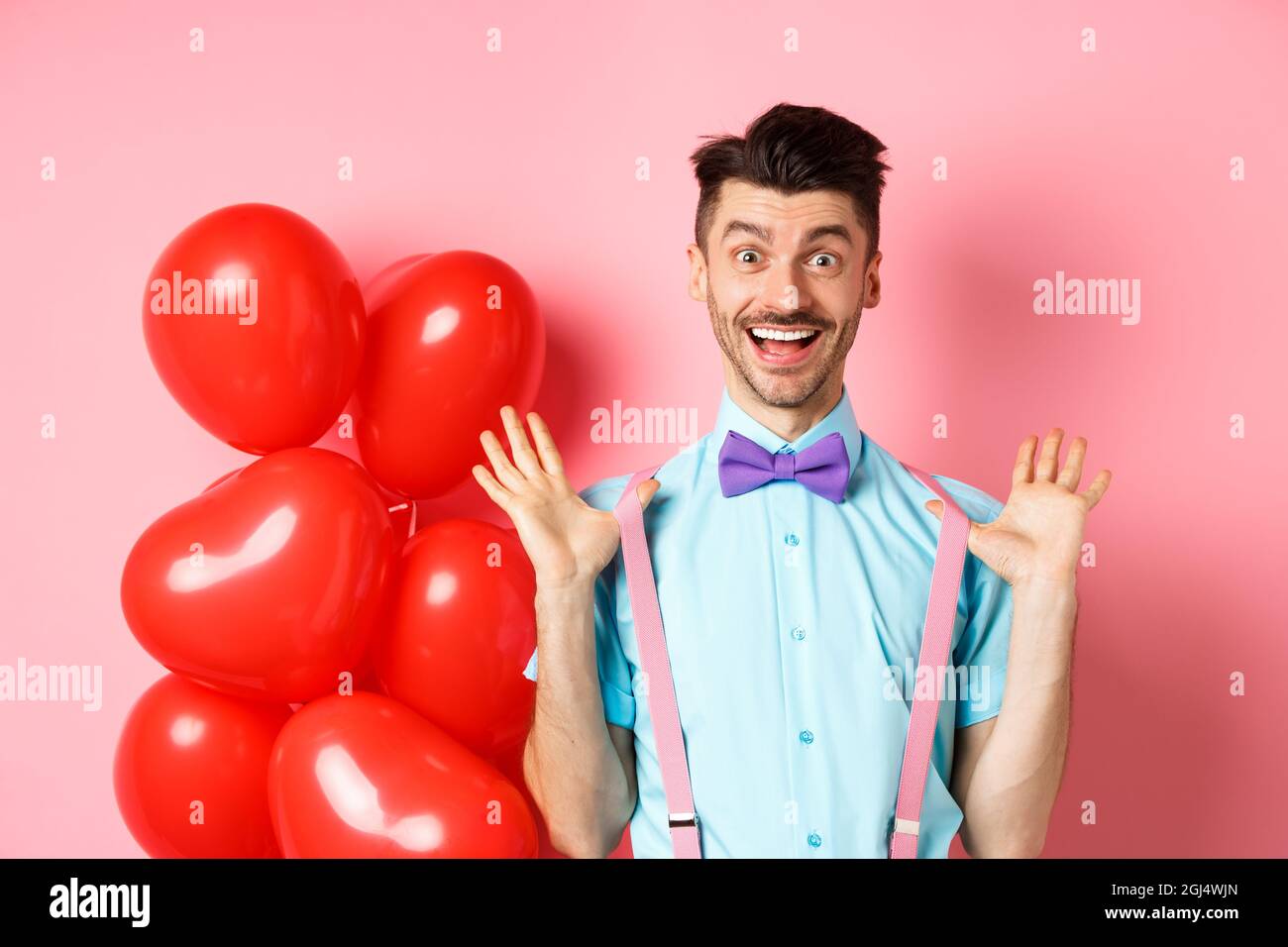 Valentinstag Konzept Glucklicher Junger Mann Der Uberrascht Aussieht Die Hande Freudig Hochhebt Und In Der Nahe Grosse Rote Herzen Und Rosa Hintergrund Feiert Stockfotografie Alamy
