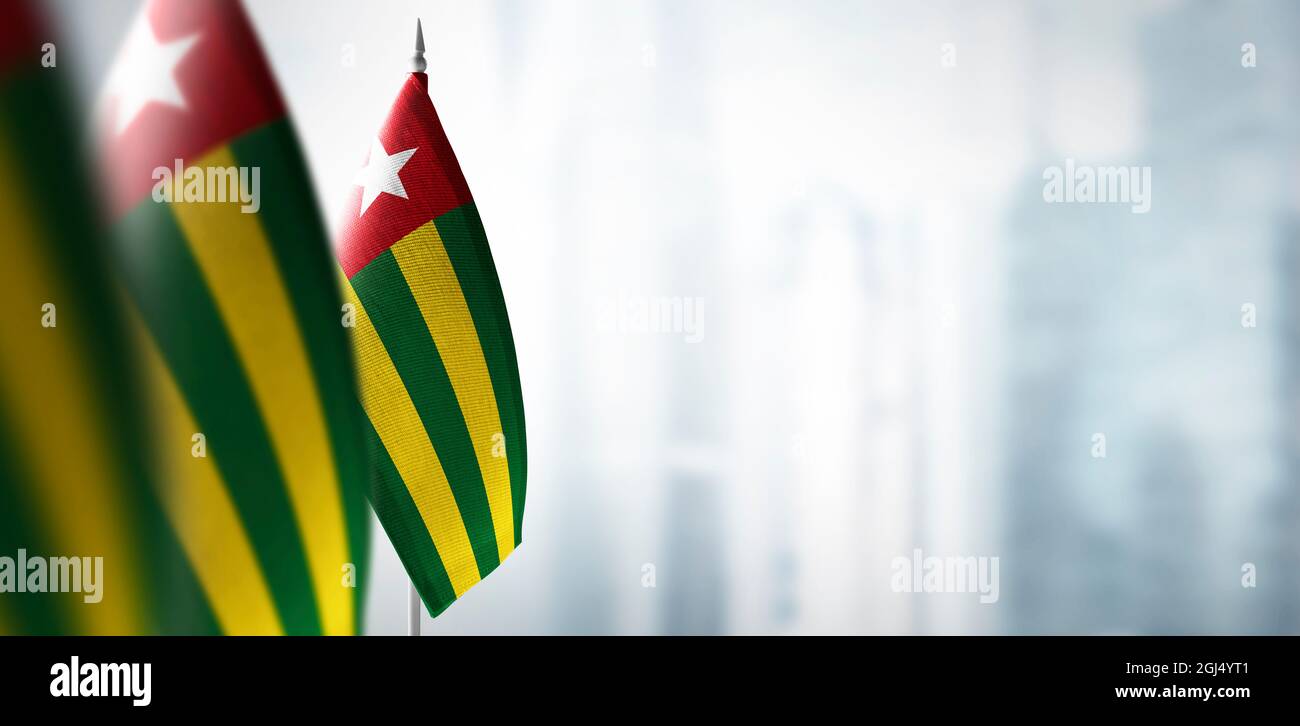 Kleine Flaggen von Togo auf einem verschwommenen Hintergrund der Stadt Stockfoto
